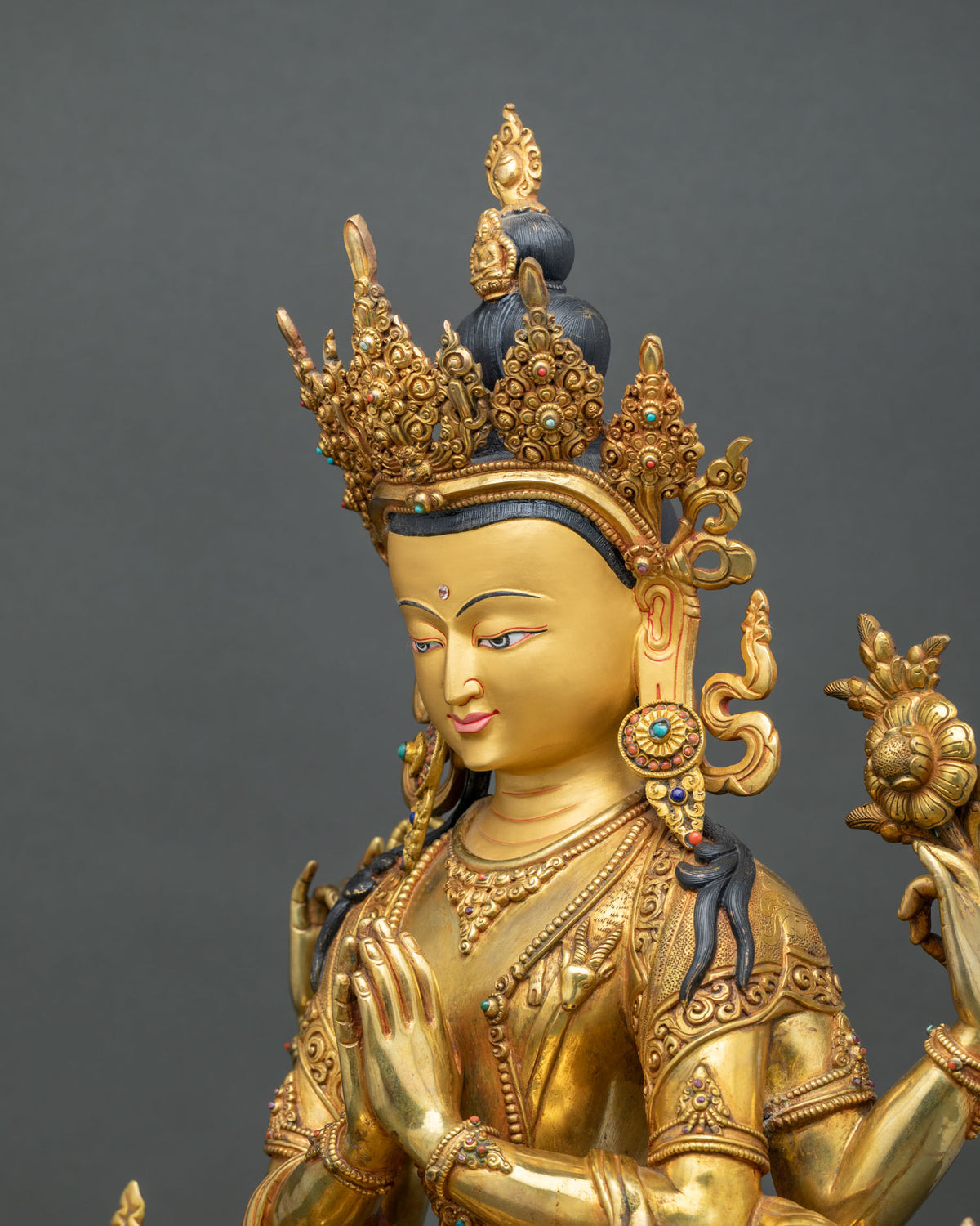 Side profile of Nepalese Chenrezig statue with ornate crown, earrings and semi-precious stones