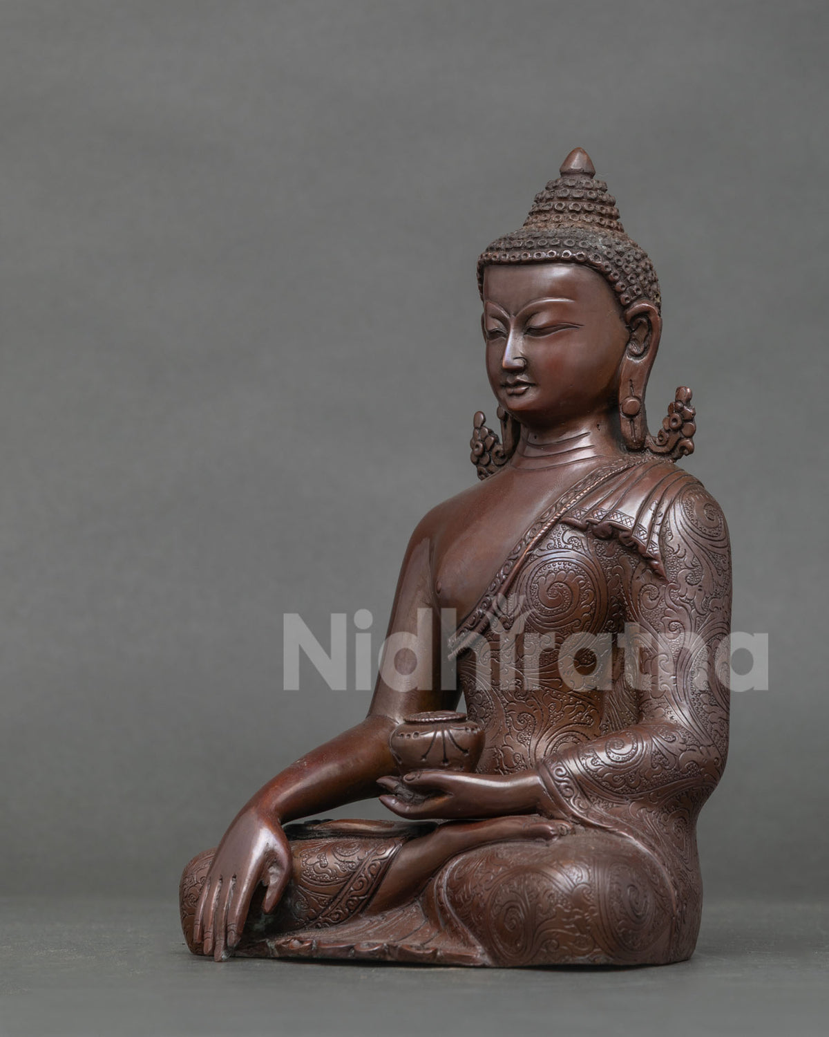 Side profile of oxidized copper Shakyamuni Buddha statue with carved robe