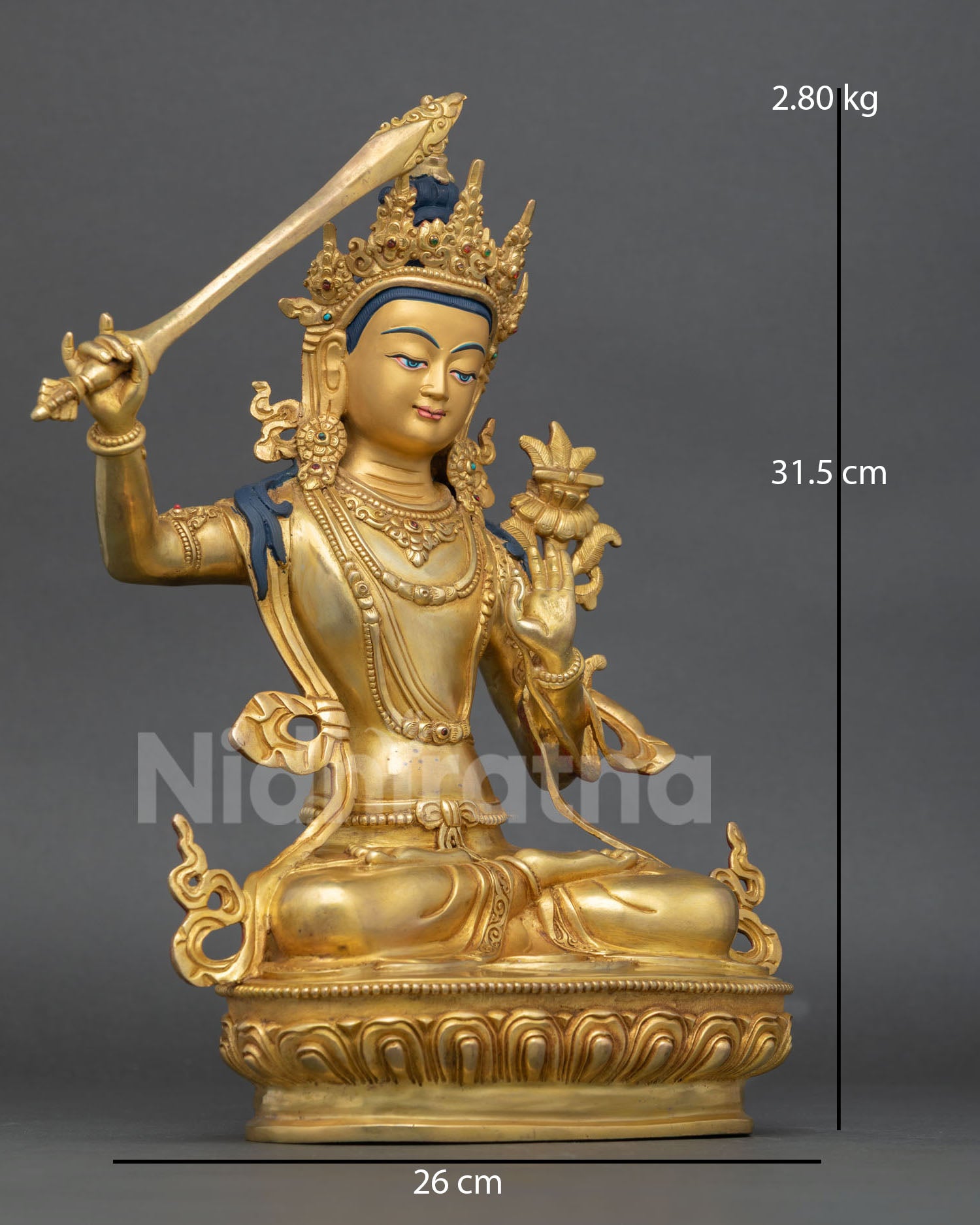 Side view of Himalayan Manjushri statue holding flaming sword of wisdom seated on lotus pedestal with intricate robes and ornaments