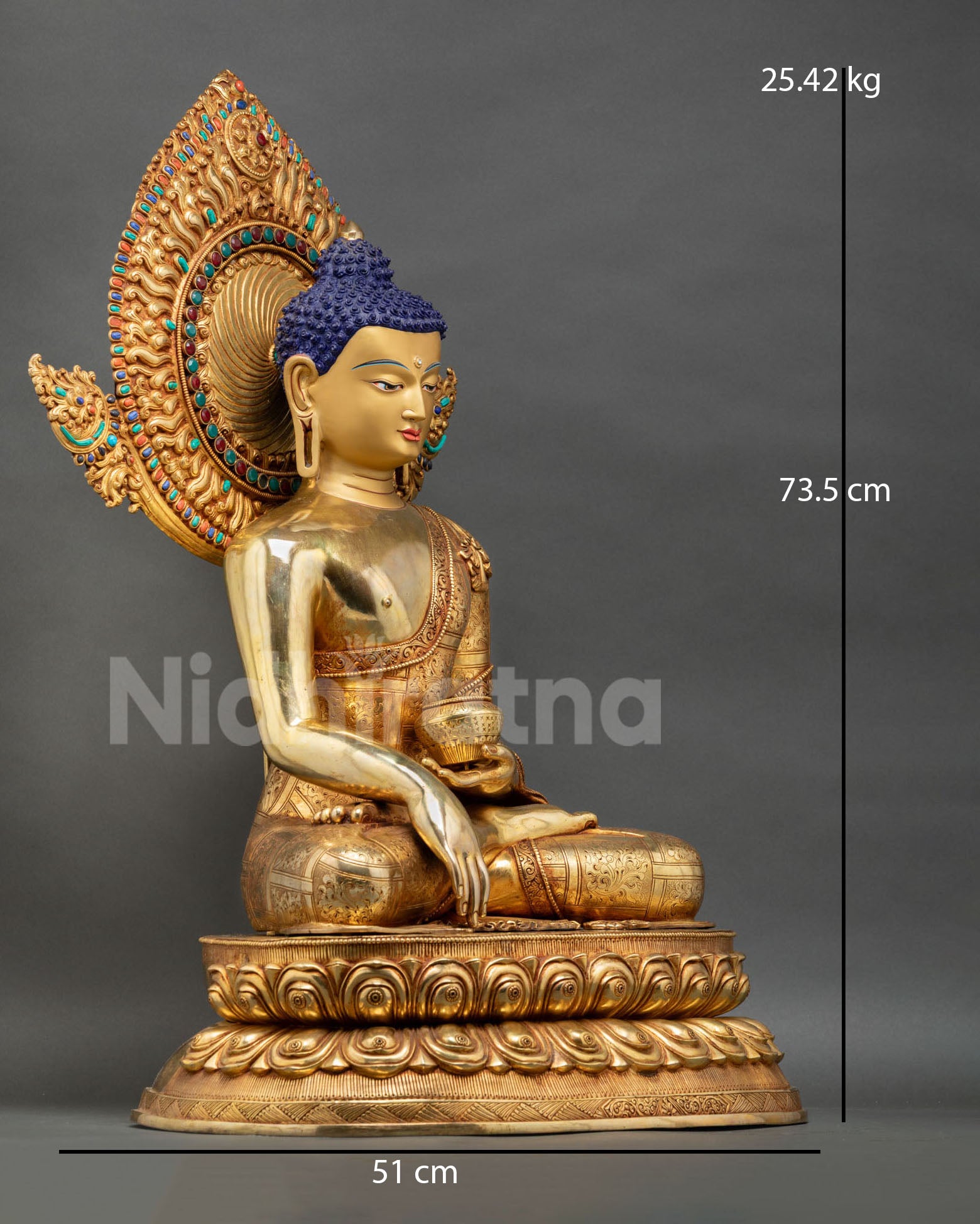 Side view of large Buddha Shakyamuni statue seated on double lotus pedestal with copper body gold finish and monastic robes for meditation and monastery interior