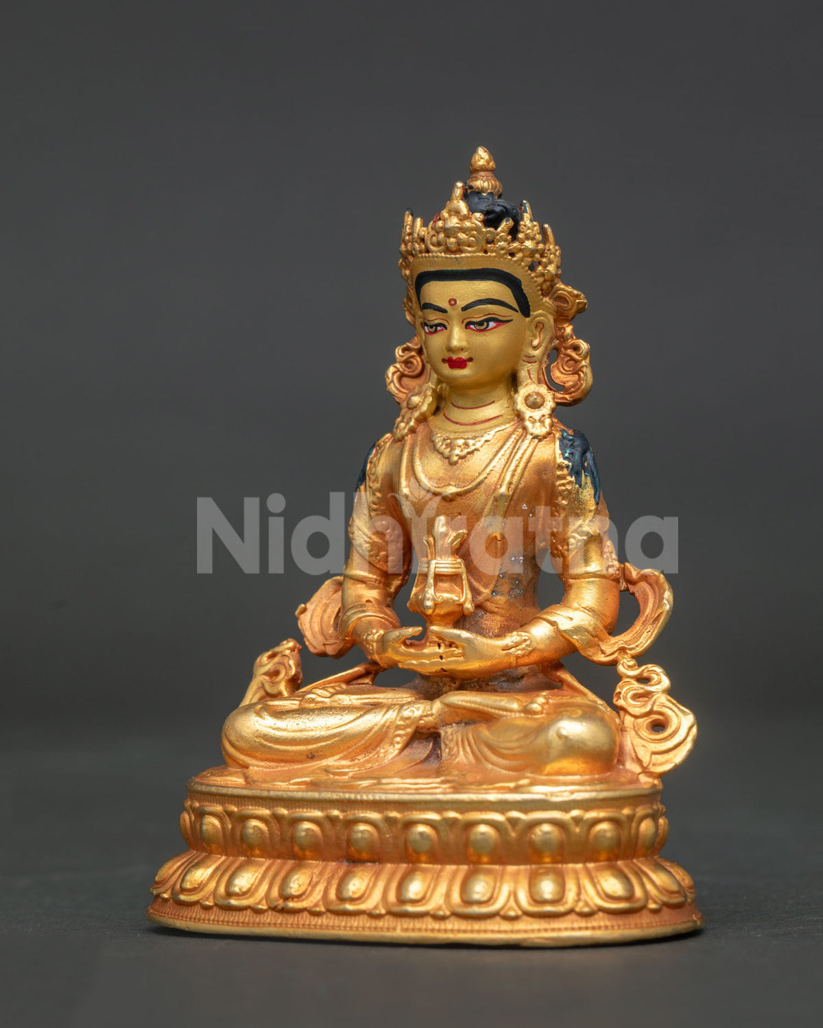 Side view of copper Amitayus Buddha statue with intricate silk garment and ornate jewelry.
