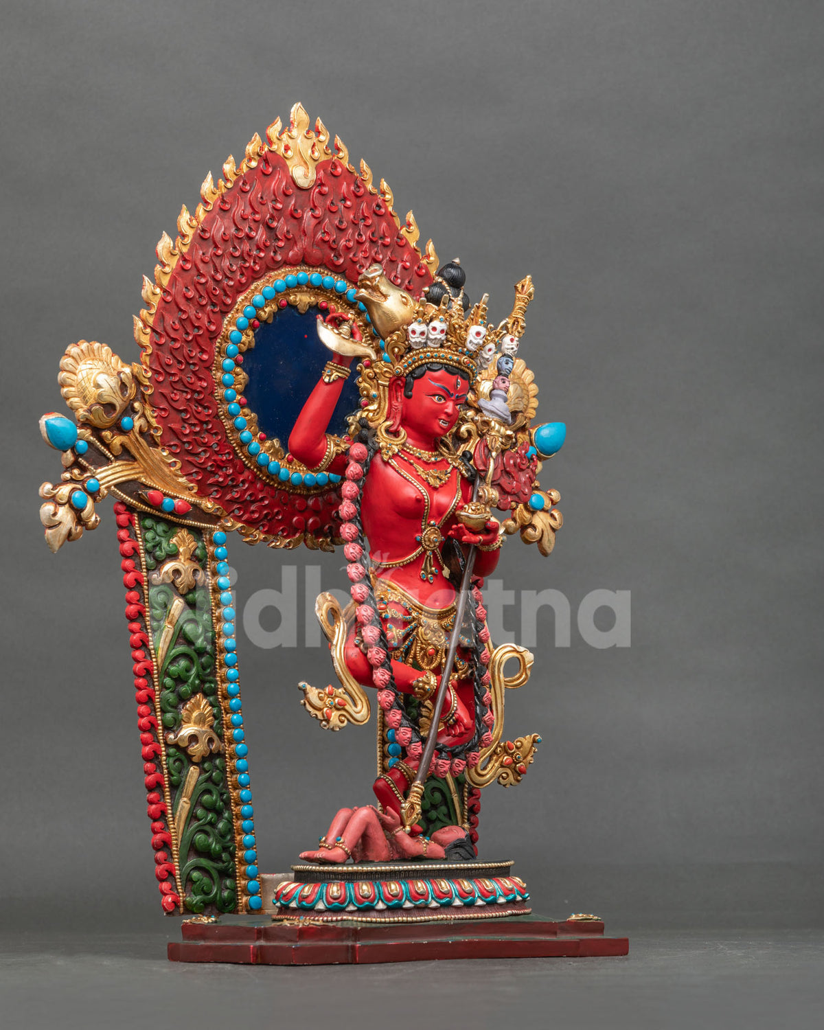 Side view of Dorje Phagmo statue with kartika knife raised before a blazing halo and floral gateway