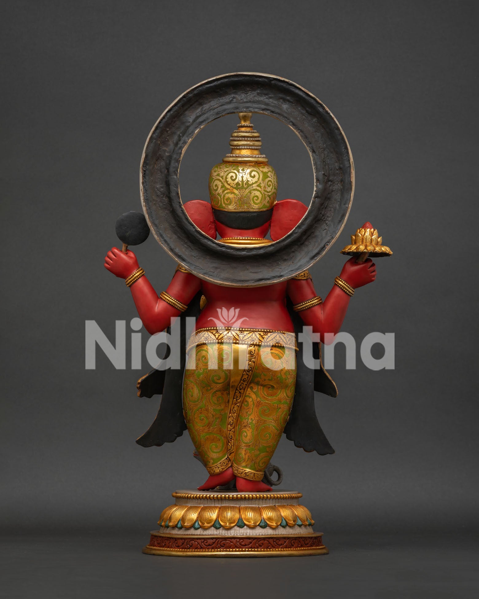 Side view of four-armed Ganesha copper statue with golden halo and lotus base