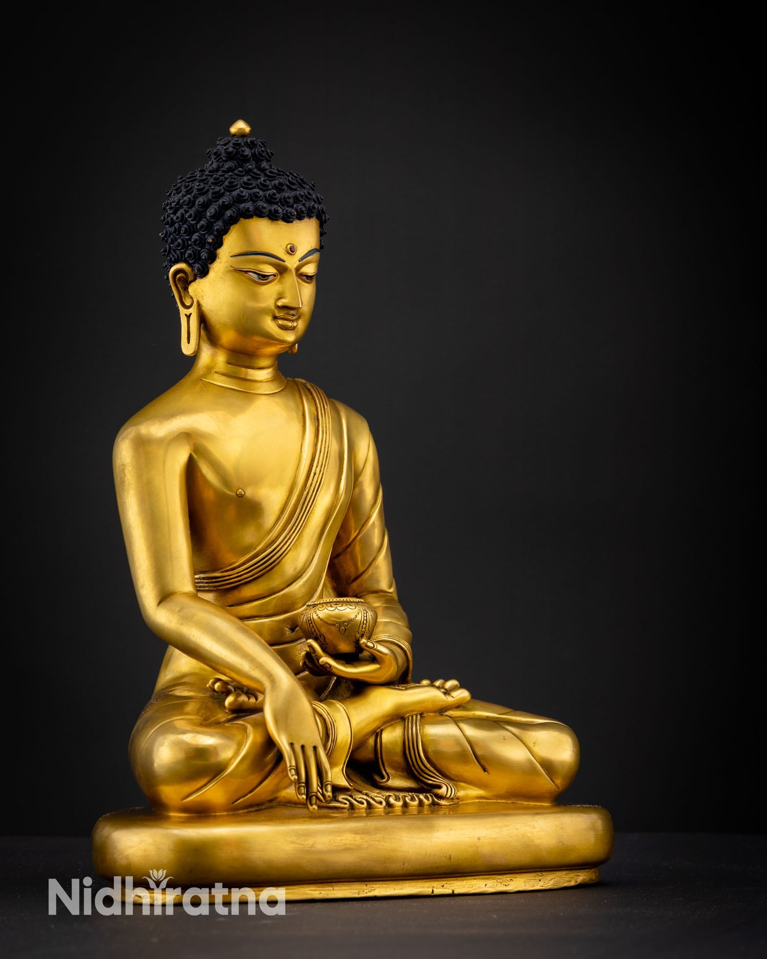 Side view of Gautama Buddha statue depicting flowing silk like robe folds alms bowl in hand and traditional Newari Himalayan craftsmanship