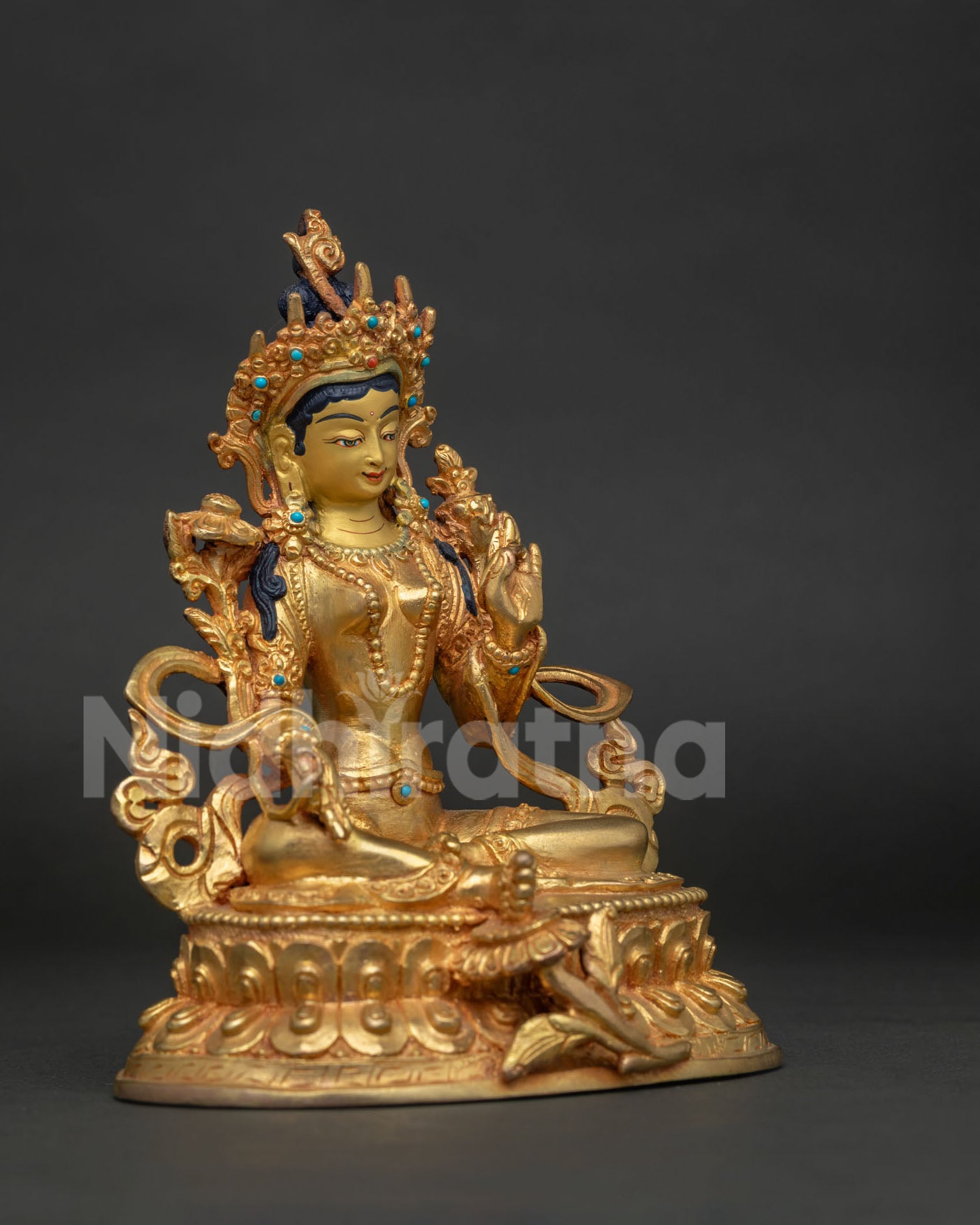 Side view of gold fire gilded Green Tara statue with blessing gesture and extended leg.