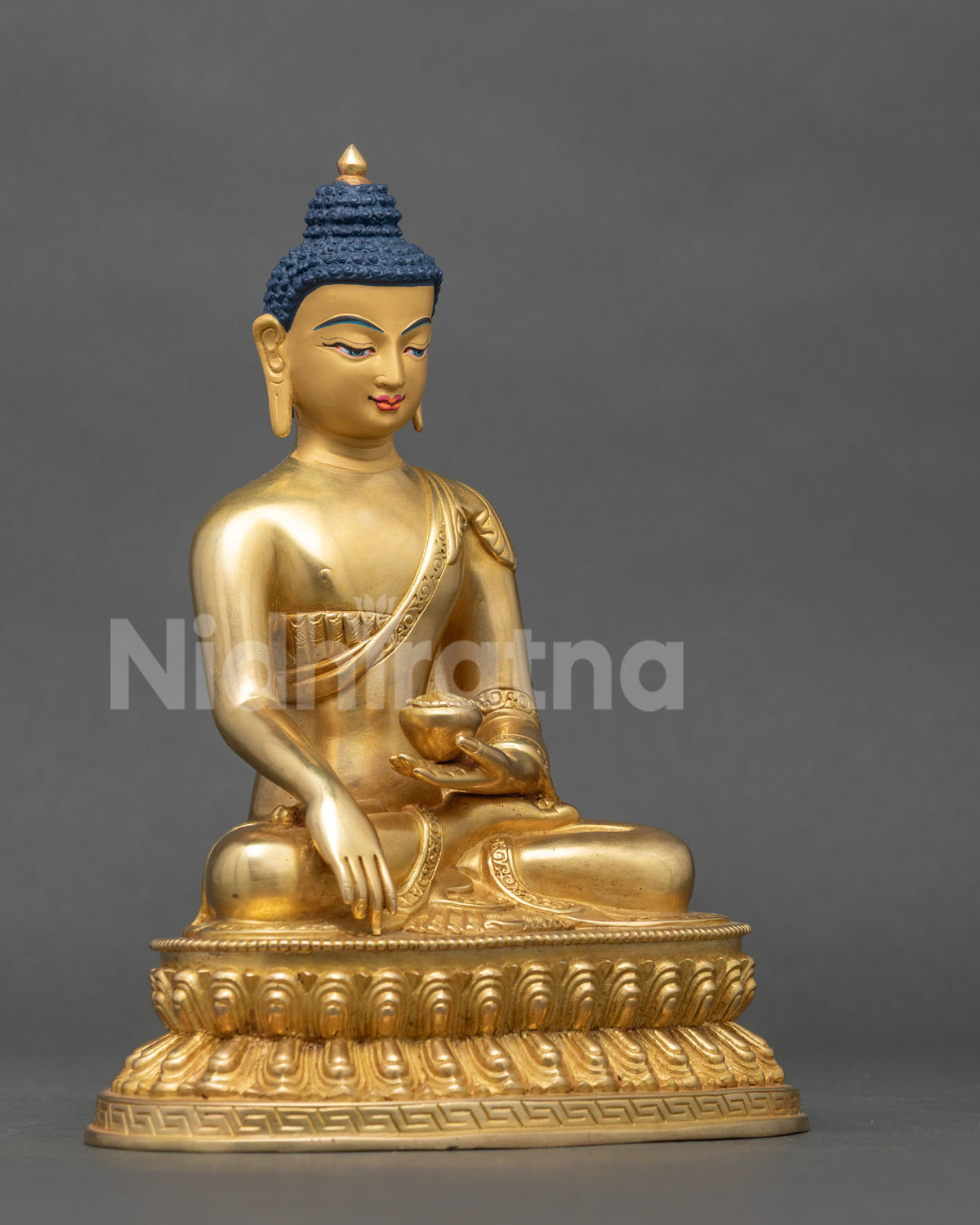 Side view of gold fire gilded Shakyamuni buddha statue holding a begging bowl.