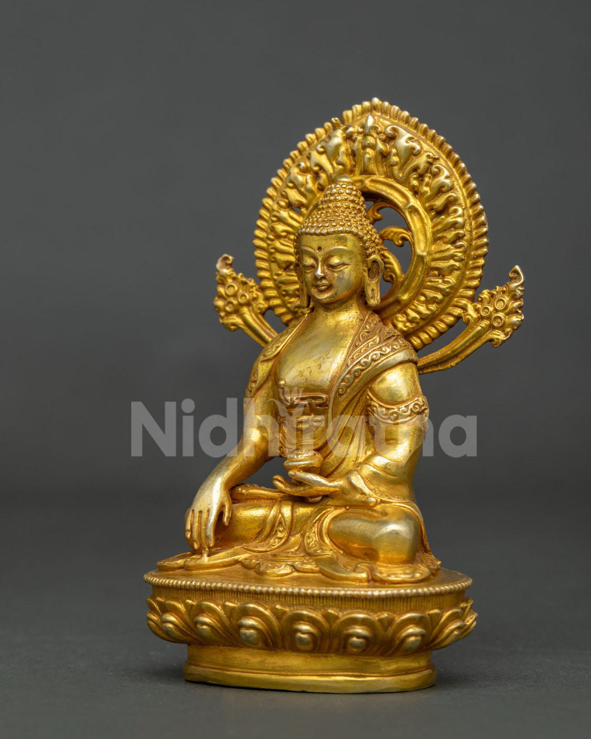 Side view of gold fire gilded shakyamuni buddha statue with intricate ornate halo.