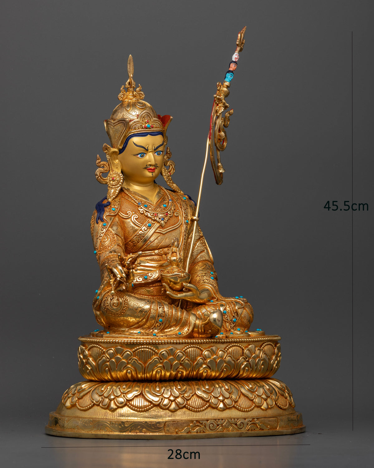 Side view of Guru Rinpoche Padmasambhava statue with vajra, skull cup and intricate floral royal garments.