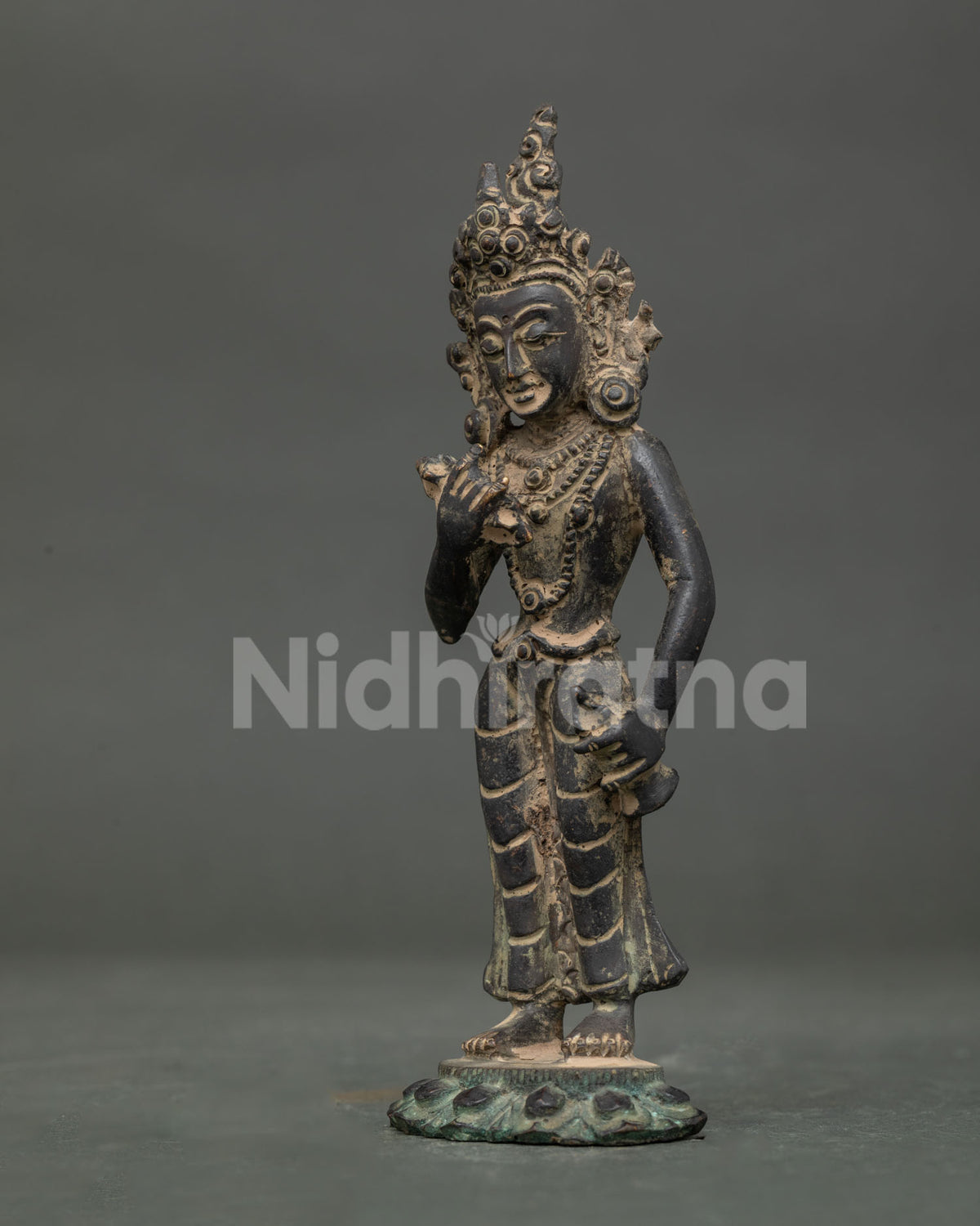 Side view of standing Vajrasattva buddhist statue with lotus pedestal and ritual bell.