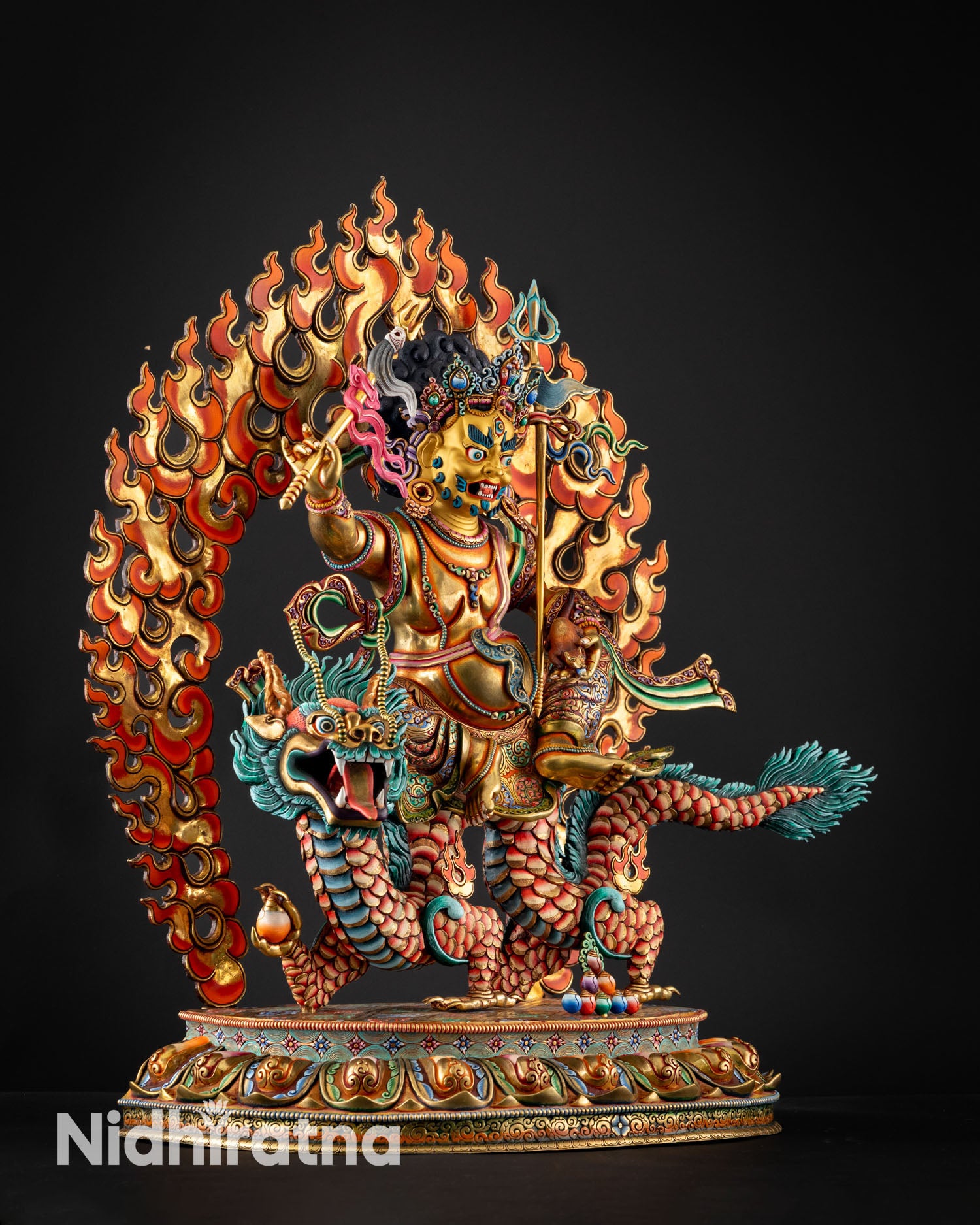 Side view of White Dzambhala statue seated on dragon blazing aureole fire copper spiritual protection sculpture