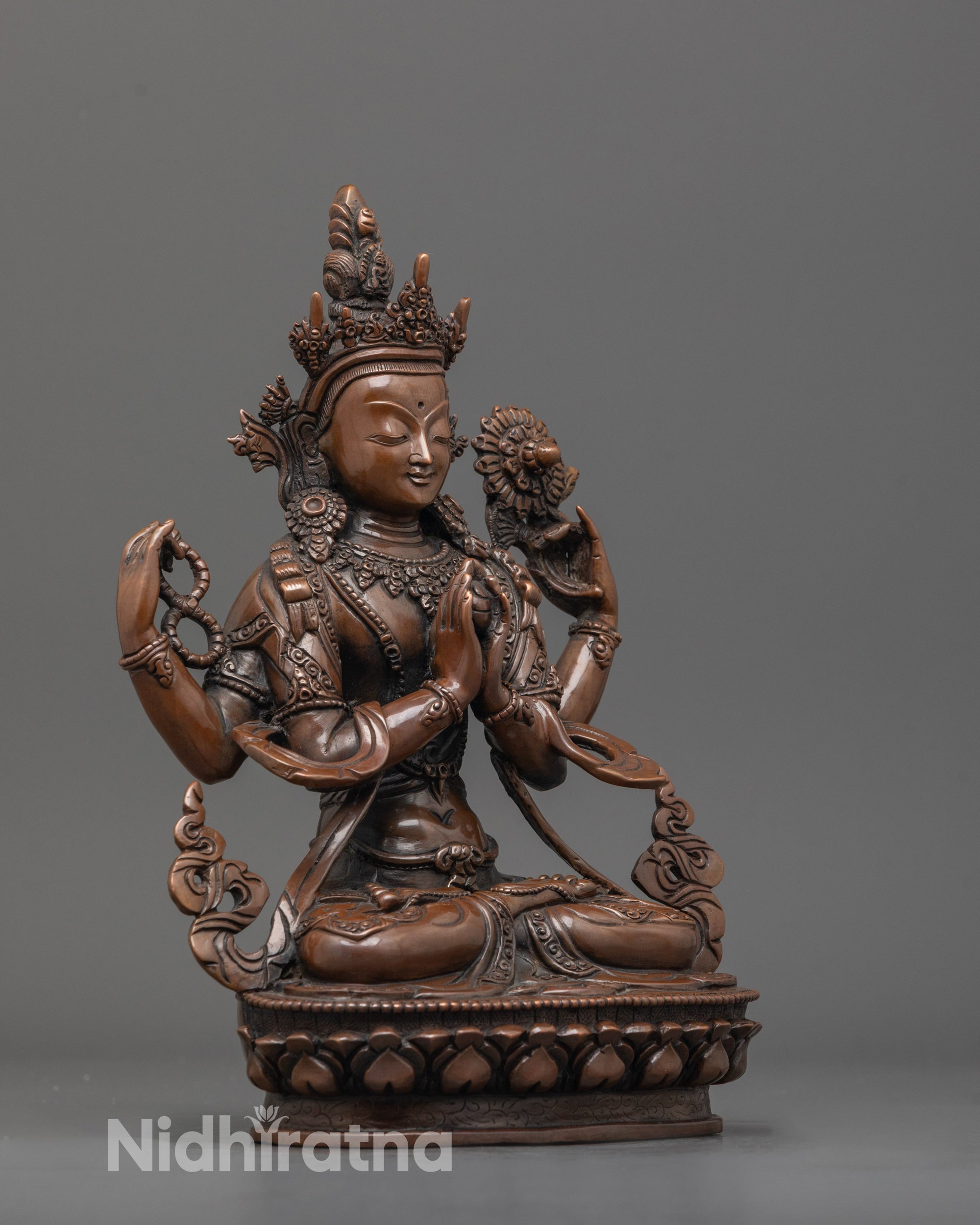 side angle of four-armed chenrezig sculpture holding sacred objects and wish gem