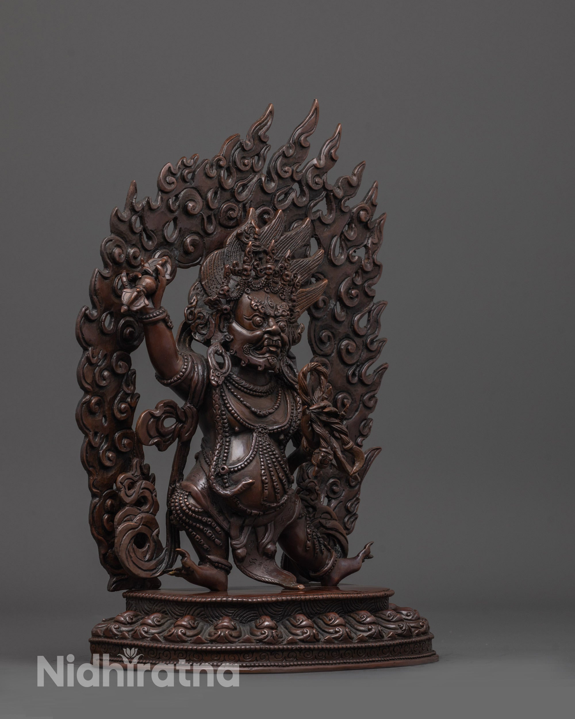 side angle of oxidized vajrapani statue with vajra and lasso in dynamic warrior posture