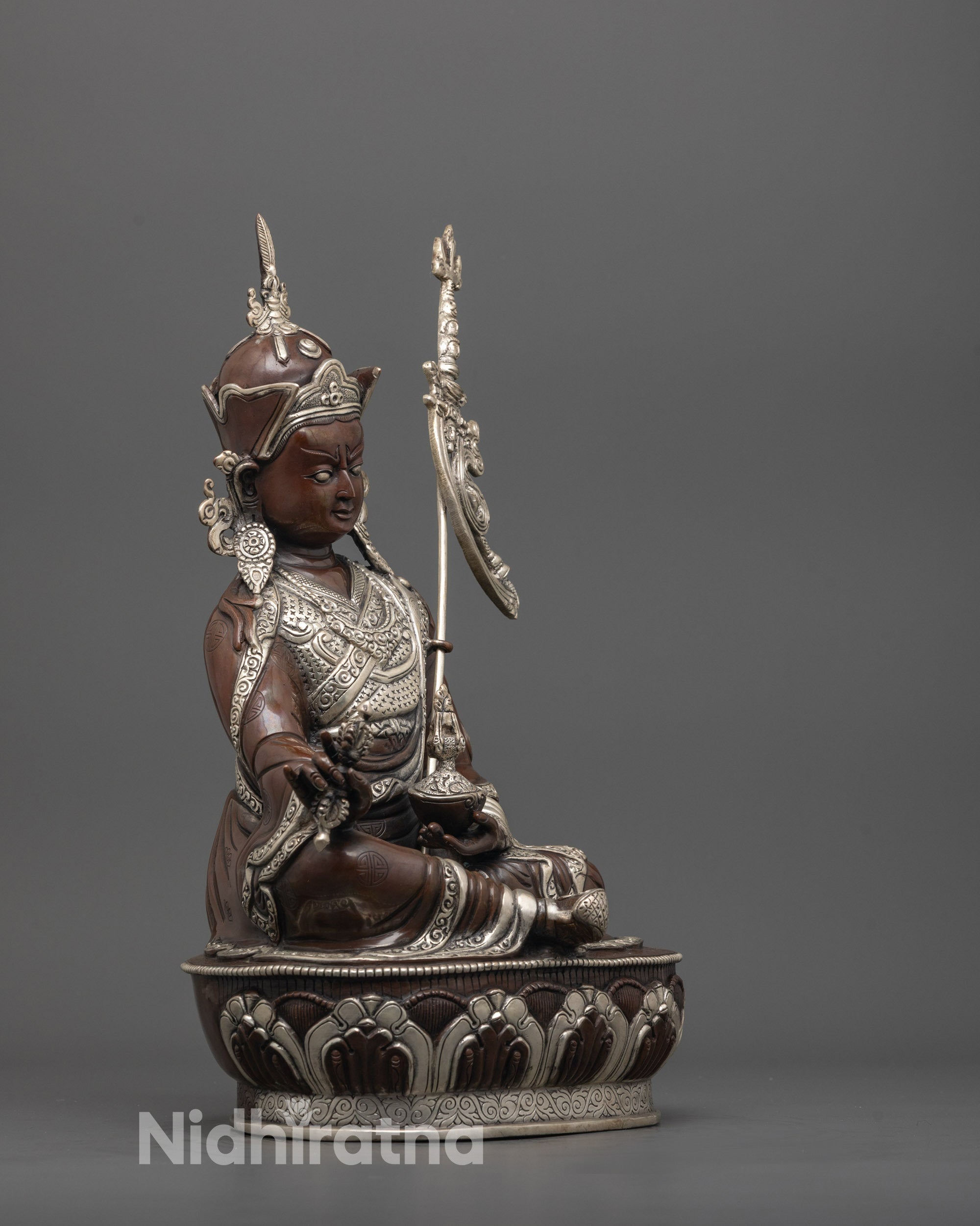 side angle of precious guru from oddiyana holding vajra, kapala, and trident