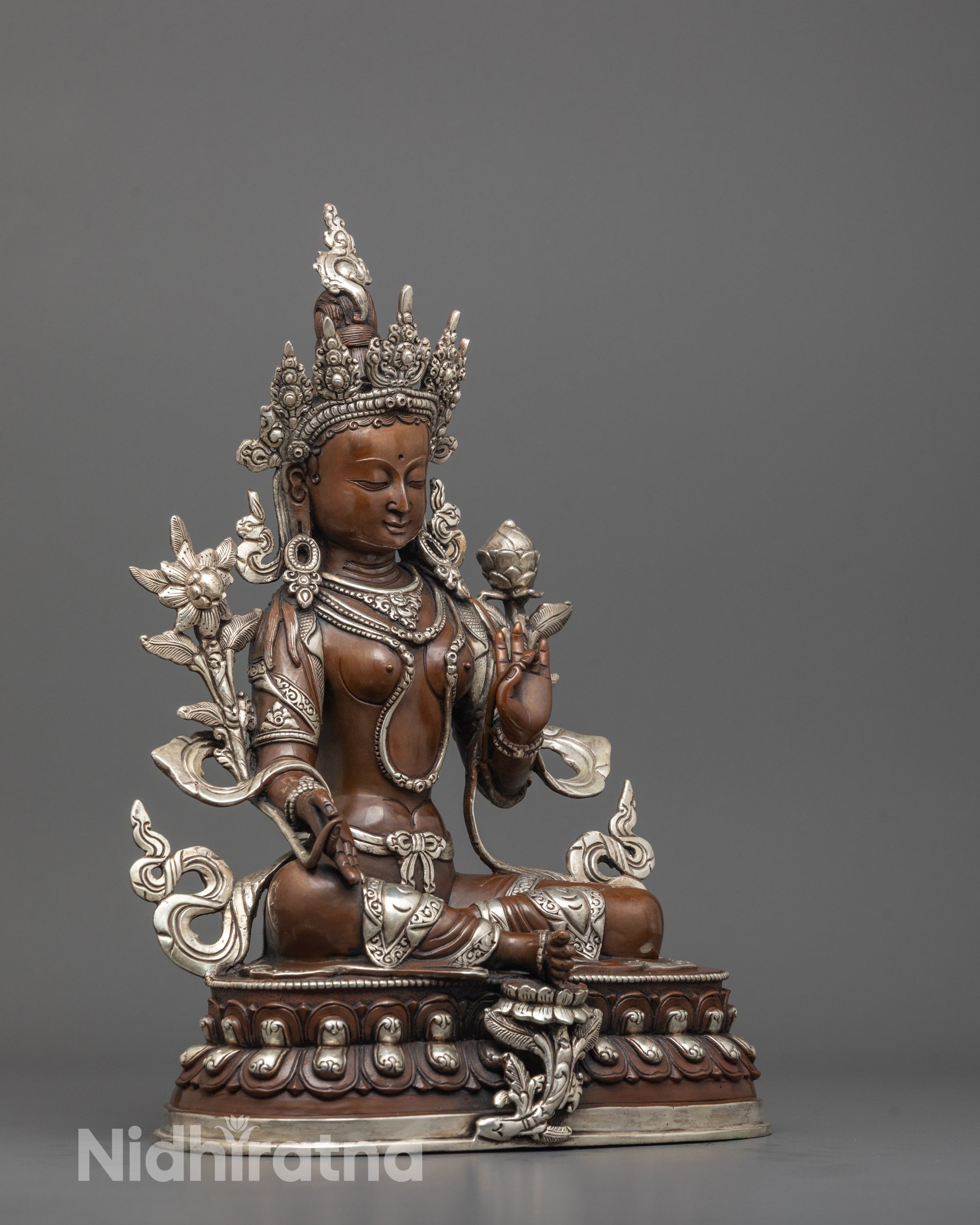 side angle of sacred green tara statue showing silver-plated robes and lotus near the foot