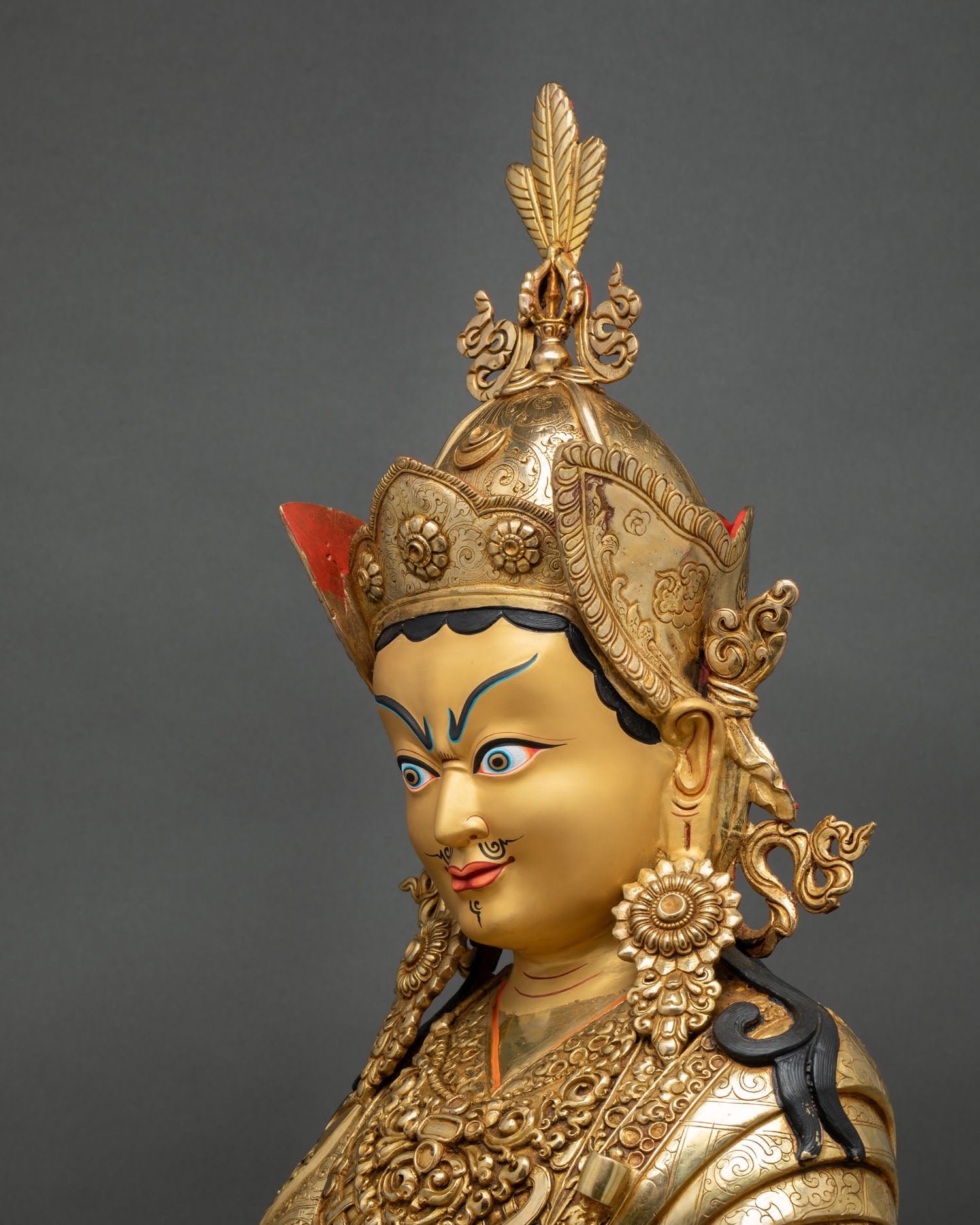 side view guru rinpoche statue seated on lotus throne, holding vajra and khatvanga staff, richly detailed robes