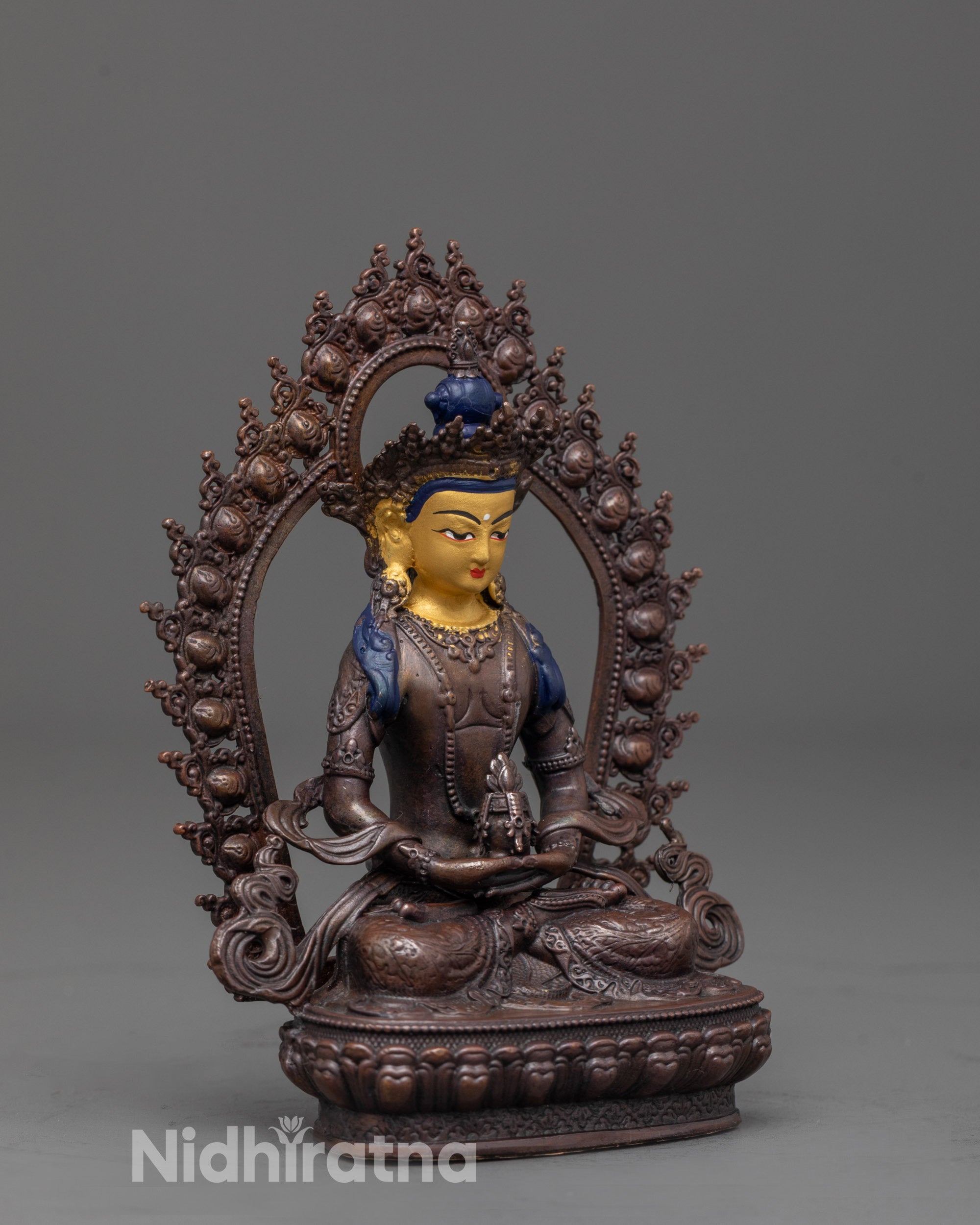 side view of amitayus sculpture seated on lotus with earthy oxidized copper tones