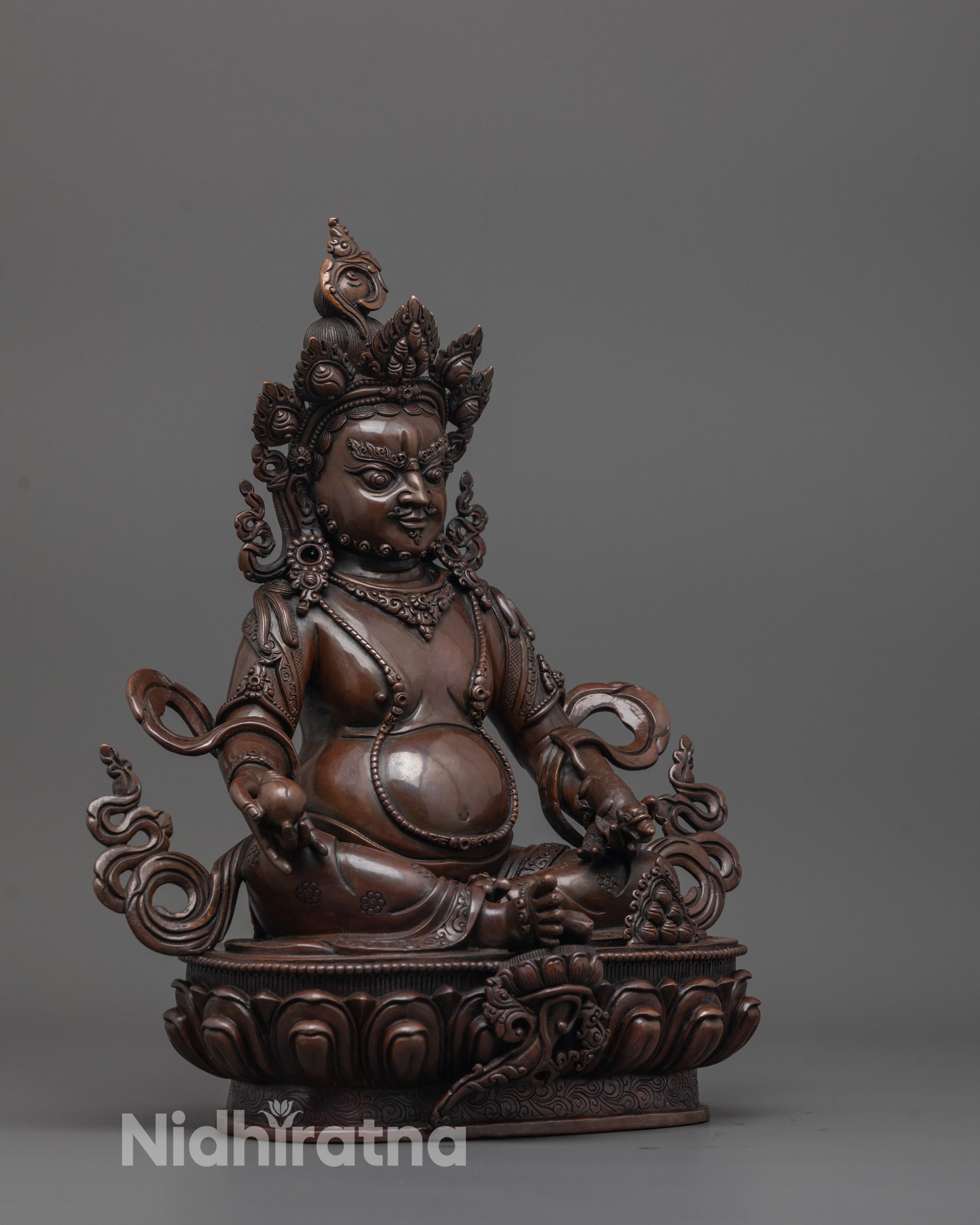 side view of dzambhala deity statue showcasing oxidized body and detailed lotus base carving