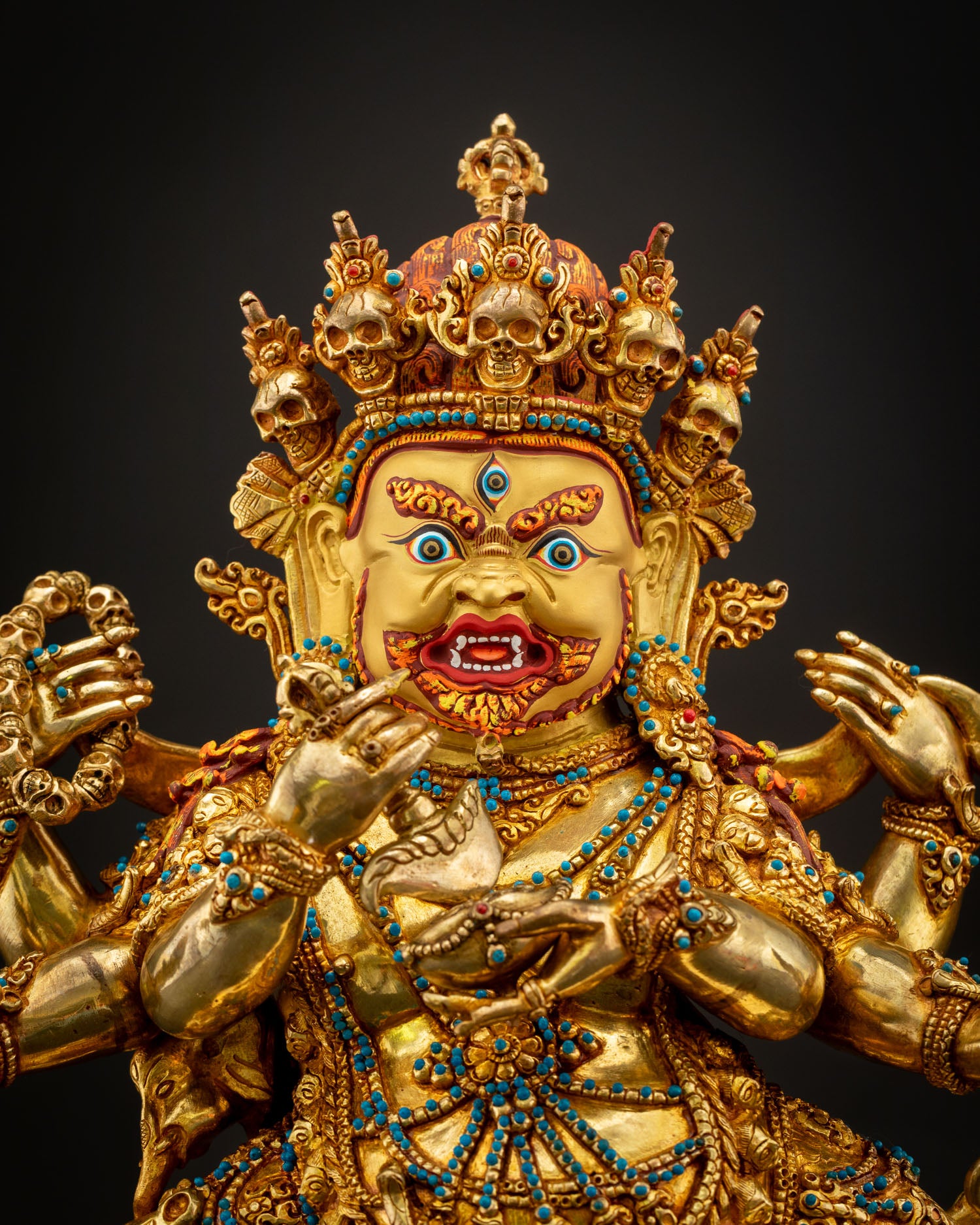 Six Armed Mahakala close up view fierce expression gold painted face semi precious stones Vajrayana wrathful protector deity detail