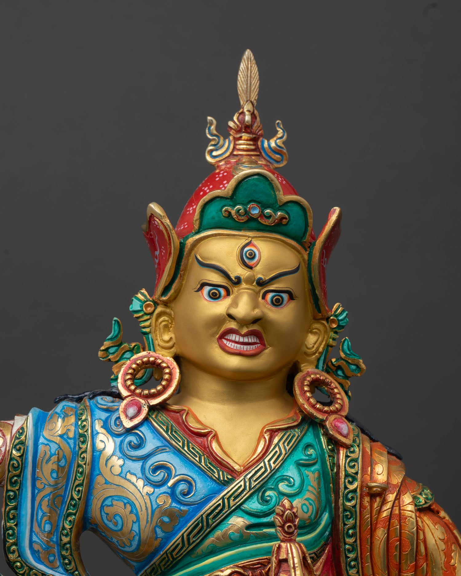 Standing Guru Rinpoche close up gold painted face Padmasambhava statue with radiant expression copper Tibetan Buddhist sculpture Nepal craftsmanship.