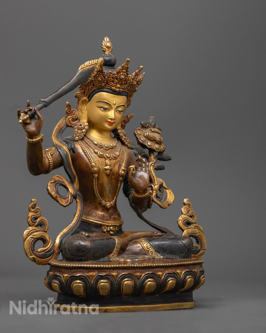 the blue utpala flower held in the left hand of the gold-plated oxidized copper Manjushri statue, representing purity and wisdom