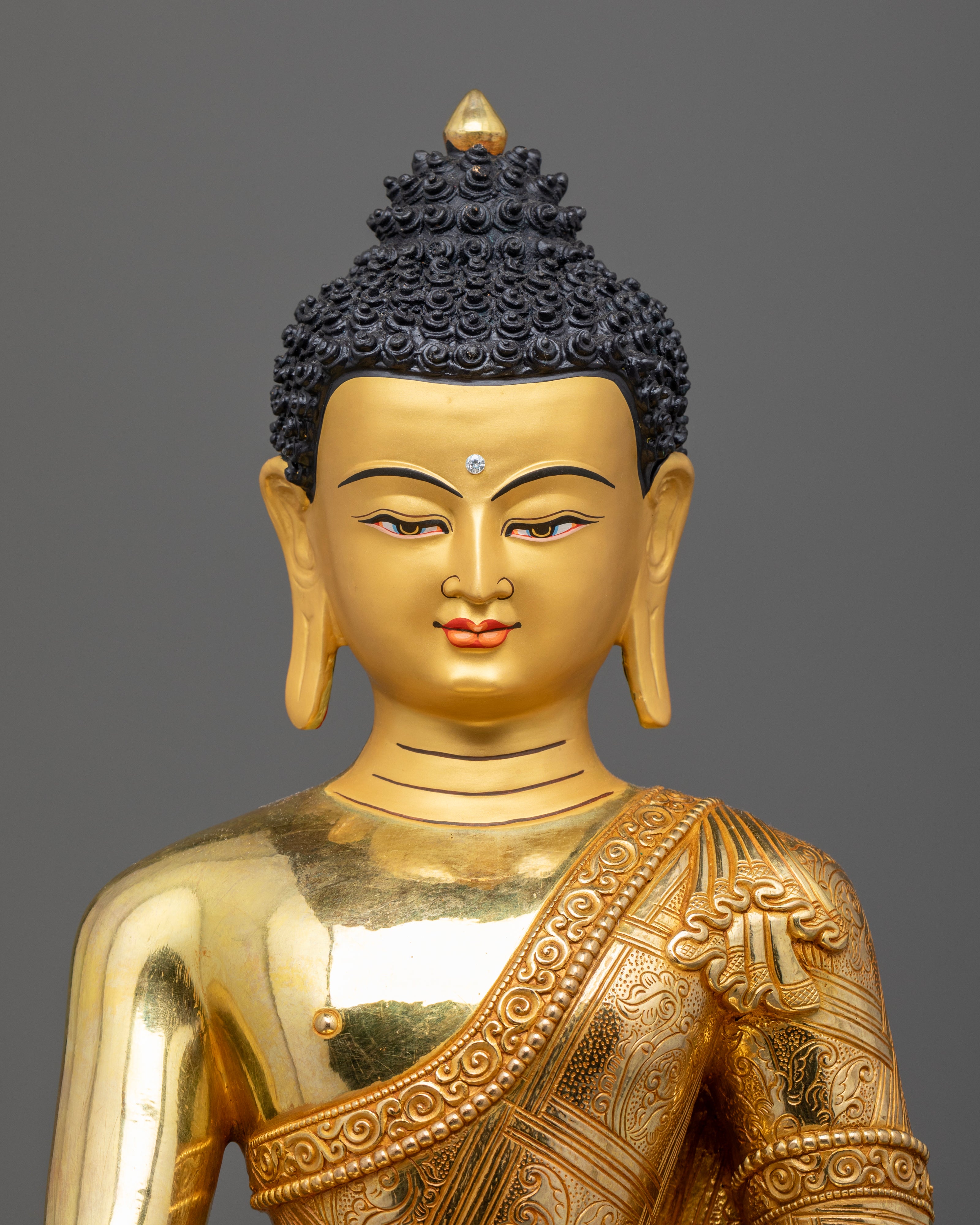 the intricately designed face of the Buddha Shakyamuni statue, showcasing the 24k gold plating and serene expression that reflect its divine craftsmanship.