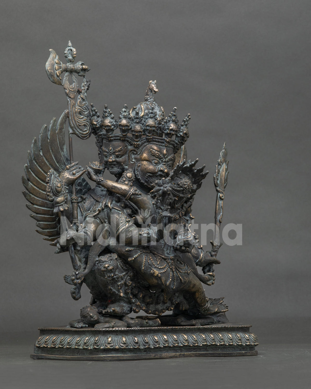 Three-quarter side view of Buddhist Hayagriva bronze statue with antique patina and ritual staff