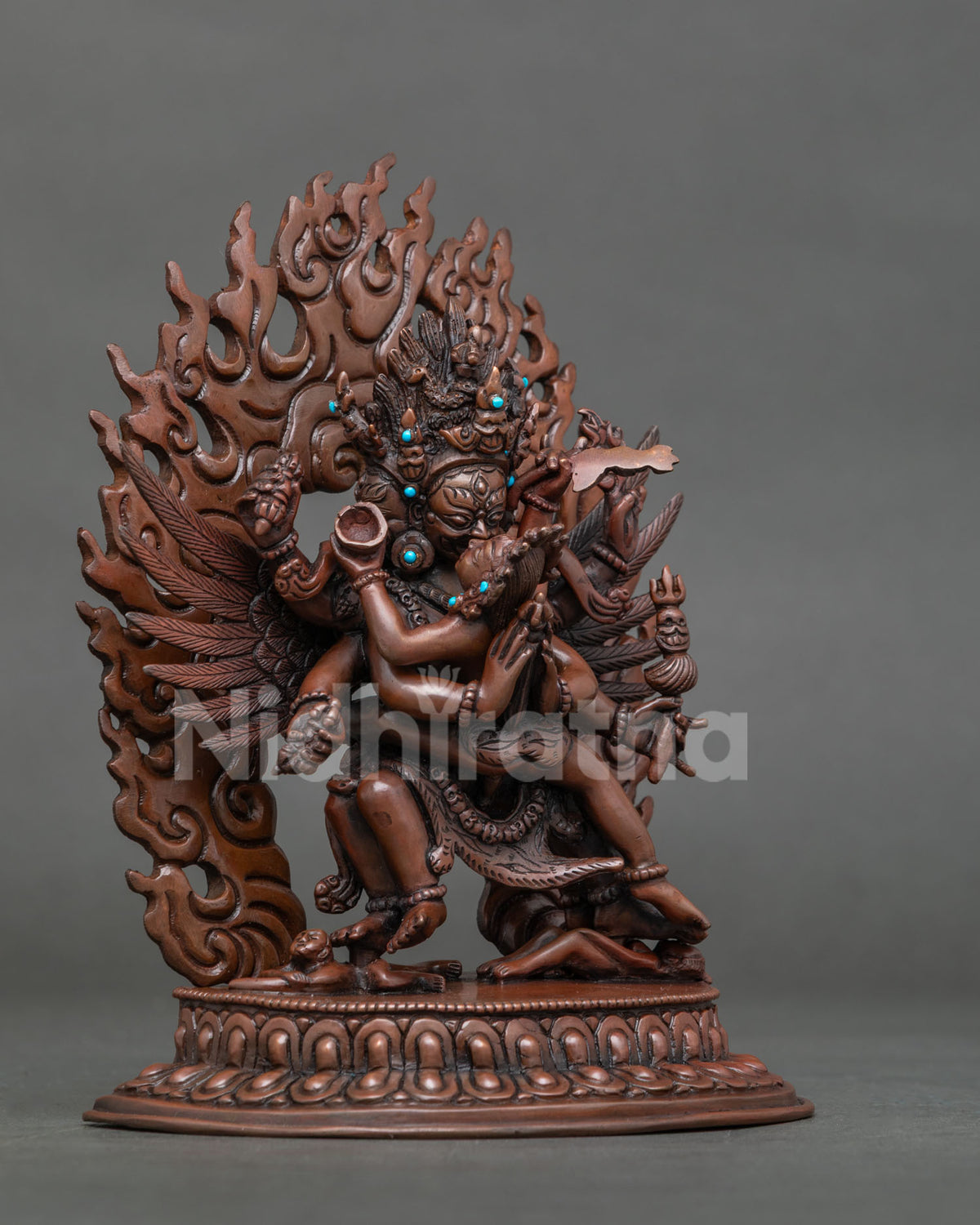 Three-quarter side view of copper Vajrakilaya statue on lotus base with ornate flame halo