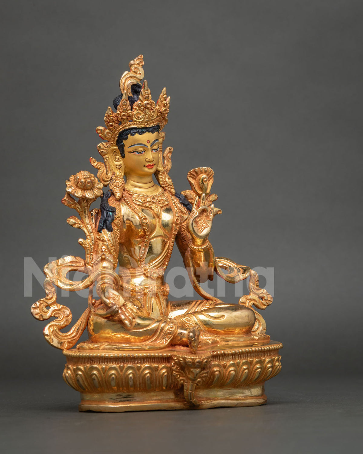 Three-quarter side view of gold-gilded Green Tara statue with carved ornaments and lotus base