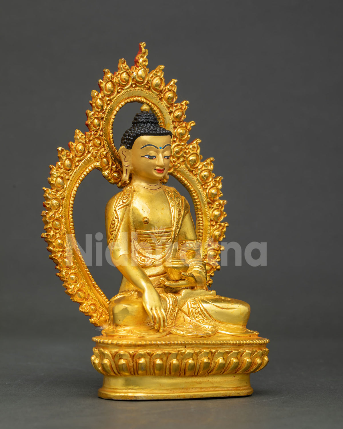 Three-quarter side view of gold-gilded Shakyamuni Buddha statue holding an alms bowl