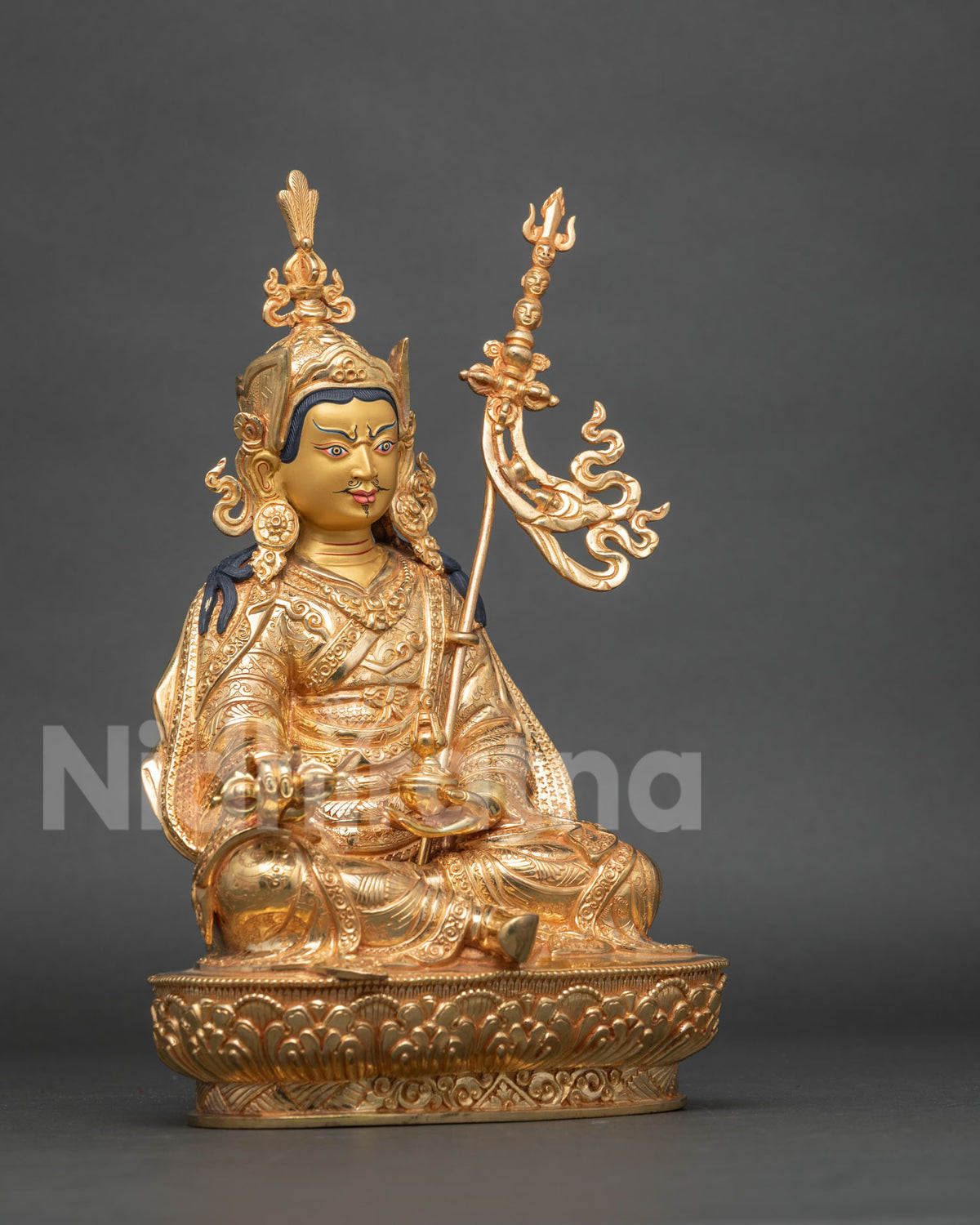Three-quarter side view of gold Padmasambhava statue with kasaya robe and carved lotus seat