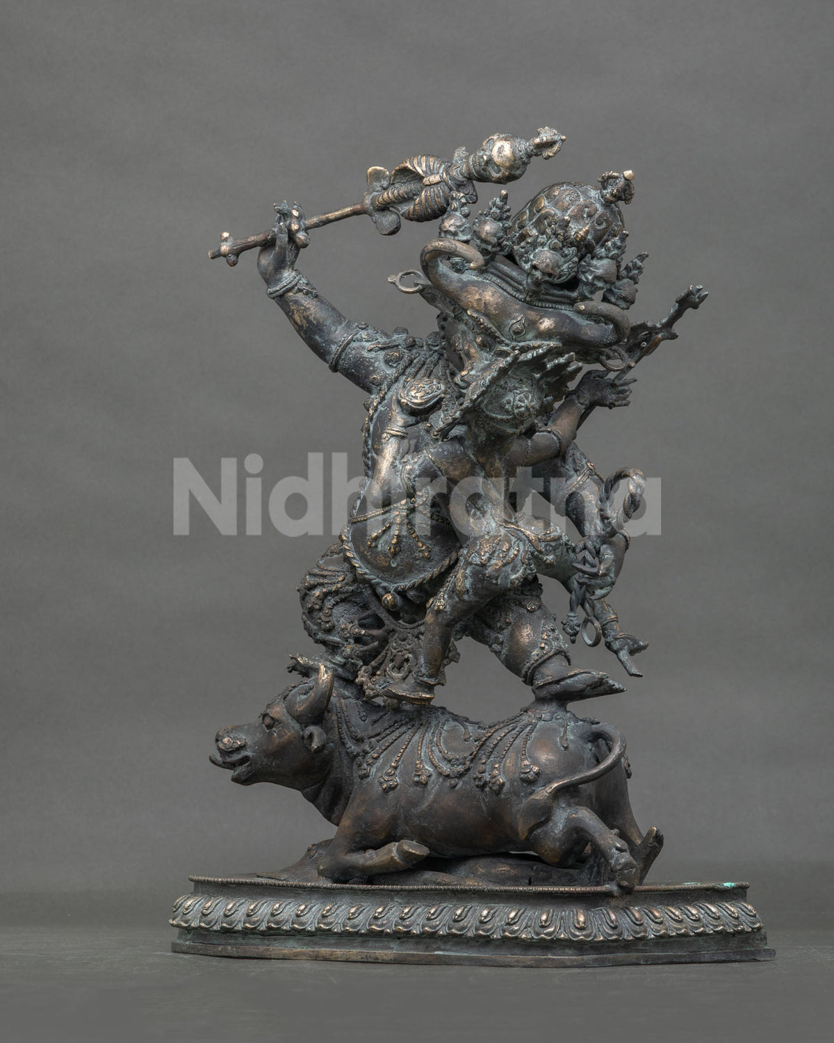 Three-quarter view of Yamantaka Vajrabhairava bronze statue showing dynamic stance on buffalo