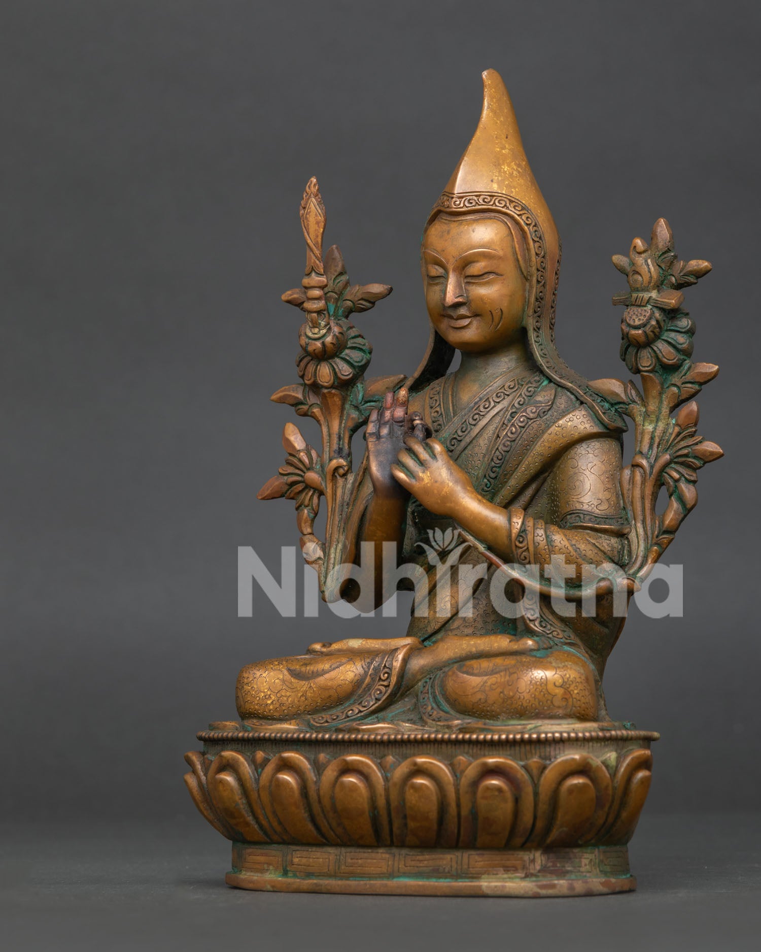 Tsongkhapa statue side view showing wisdom sword sacred scripture and blooming lotus stems.