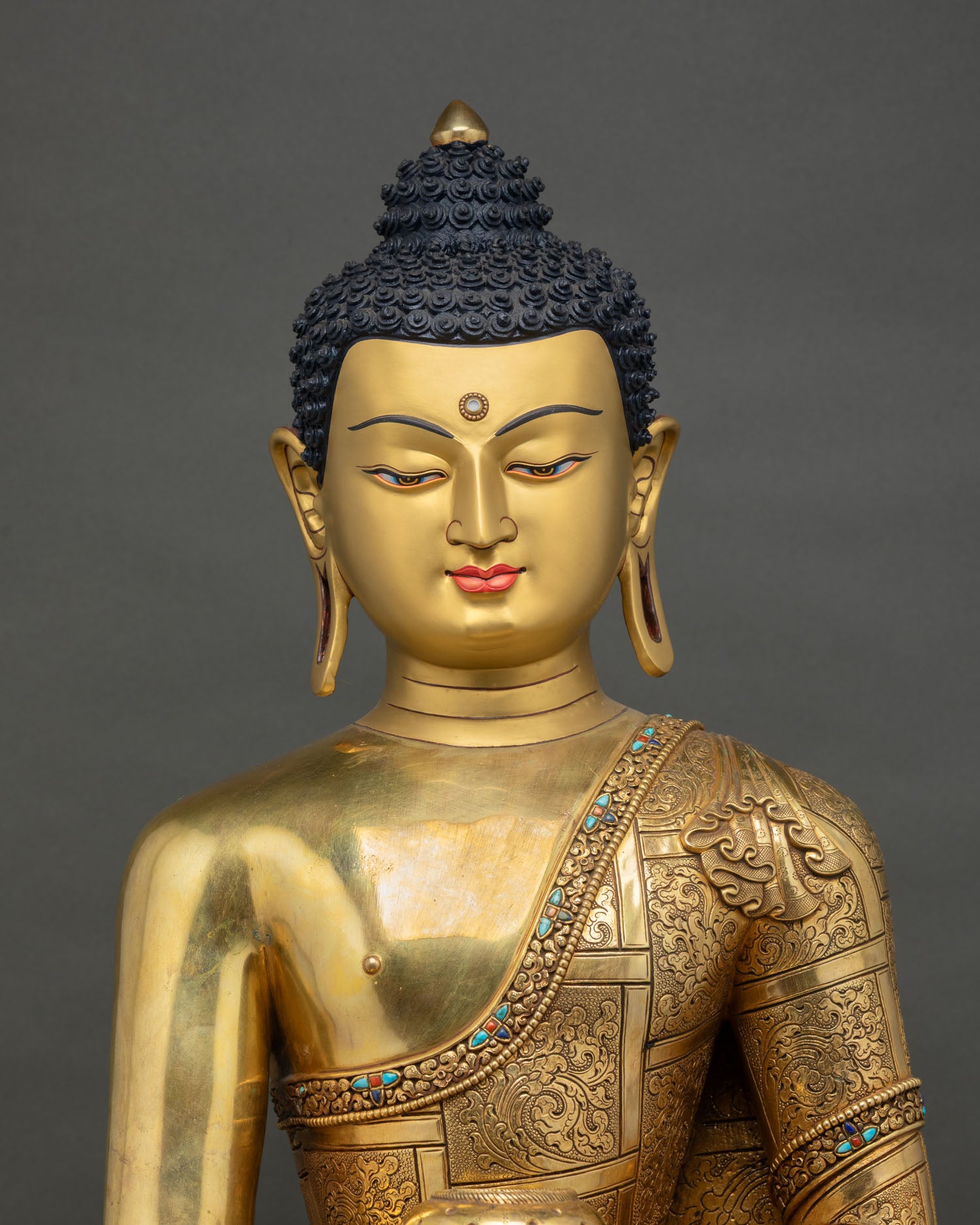 upper body close up of shakyamuni buddha statue with gold gilded robe details