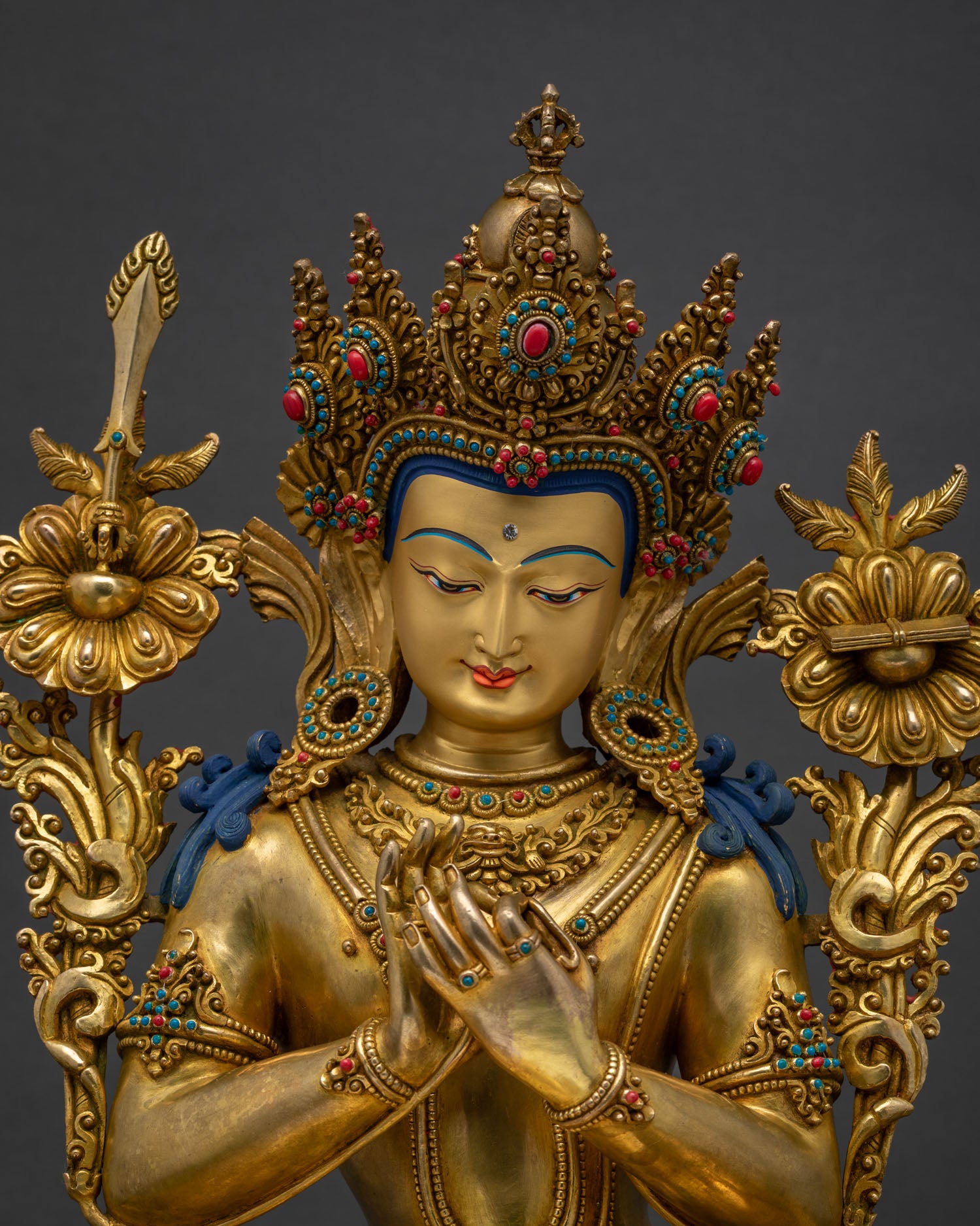 Upper body view of Tikshna Manjushri statue holding lotus stems in Dharmachakra mudra