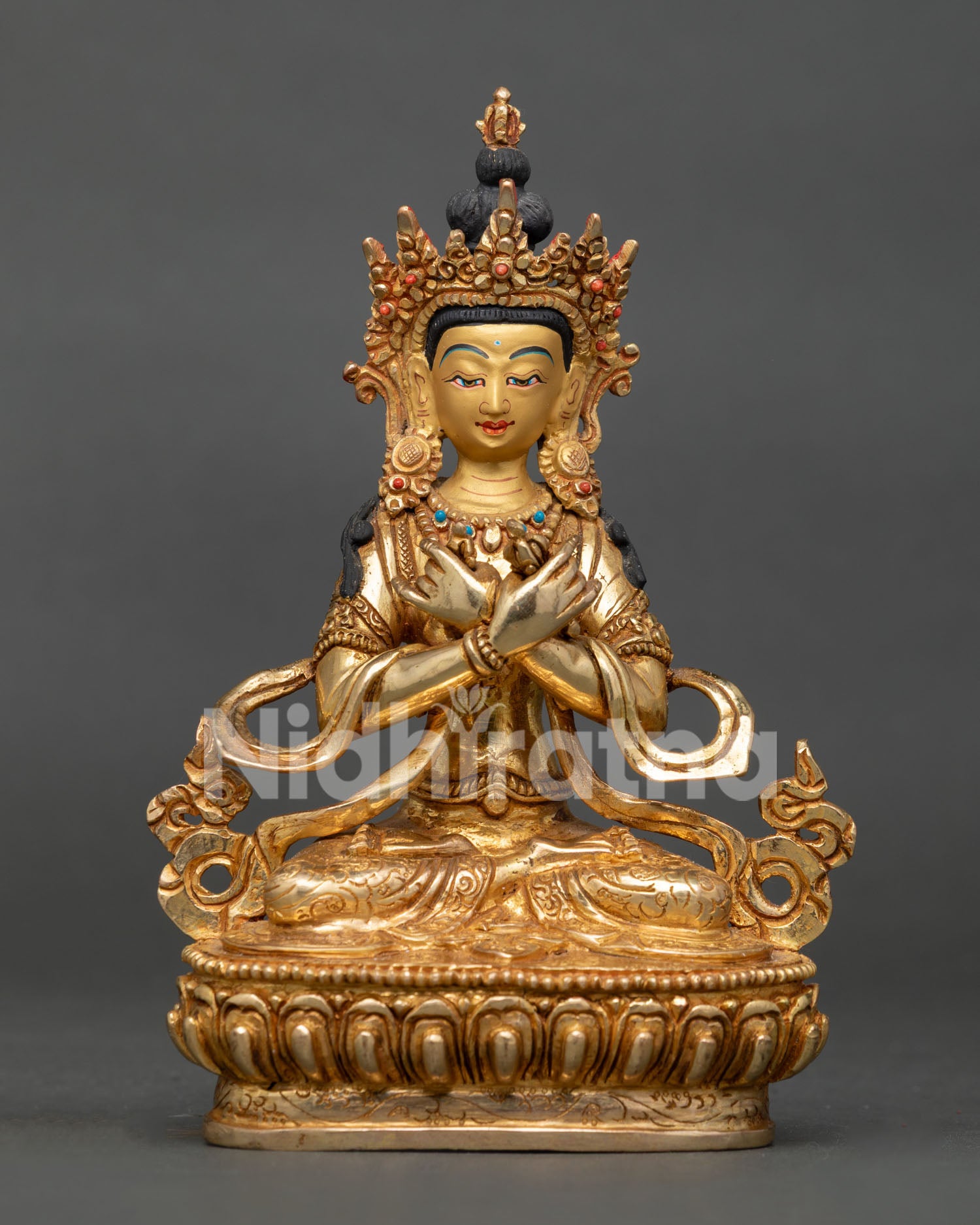 Vajradhara Buddhist deity statue seated in vajraparyanka posture holding vajra and bell on lotus pedestal.