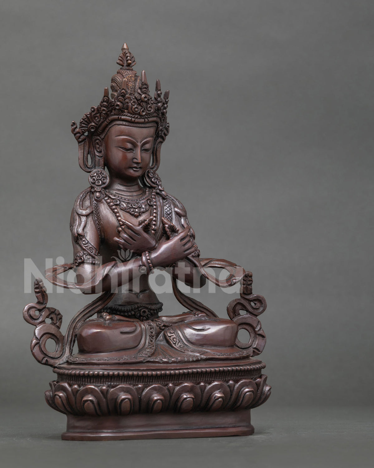 Vajradhara statue seated in vajraparyanka posture on detailed lotus pedestal.
