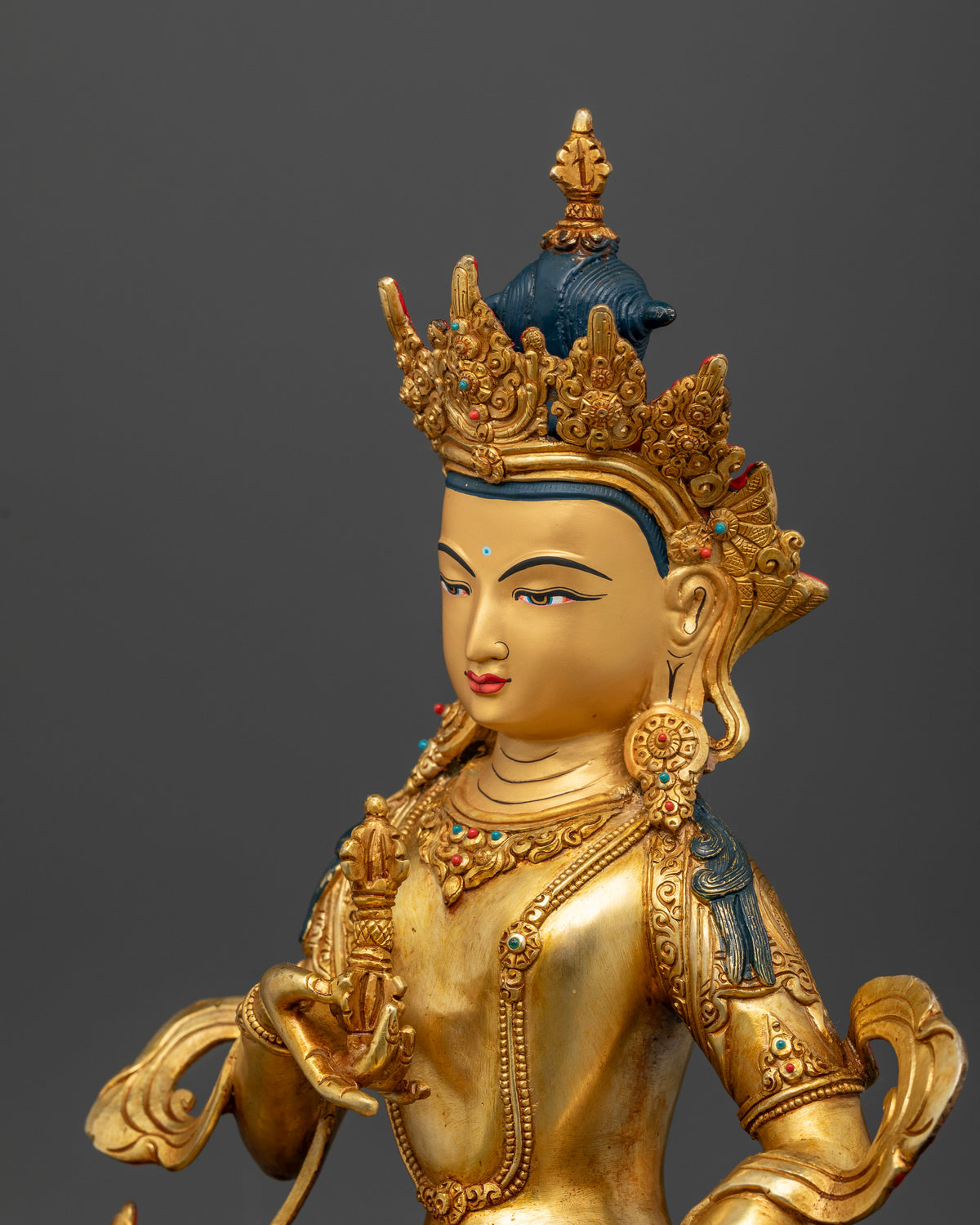 Vajrasattva statue holding vajra and bell adorned with turquoise and coral stones.