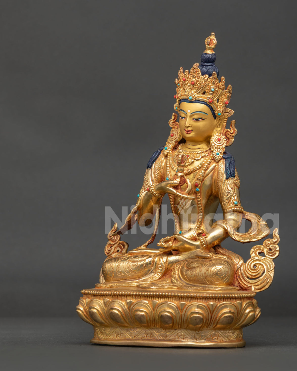 Vajrasattva statue seated on finely carved lotus pedestal holding vajra in right hand and bell in left hand.