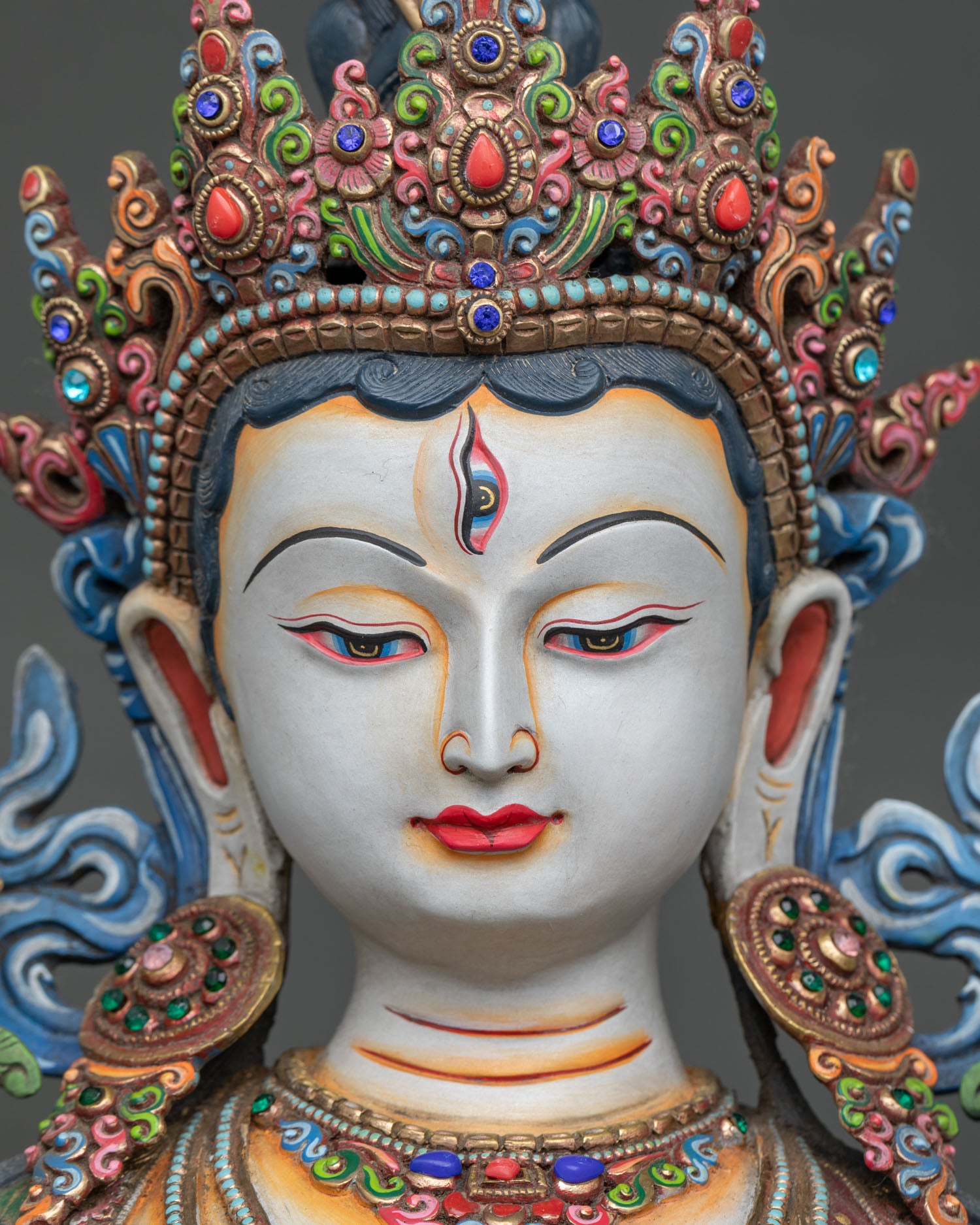 white tara face close up with serene expression gold painted face and jeweled crown