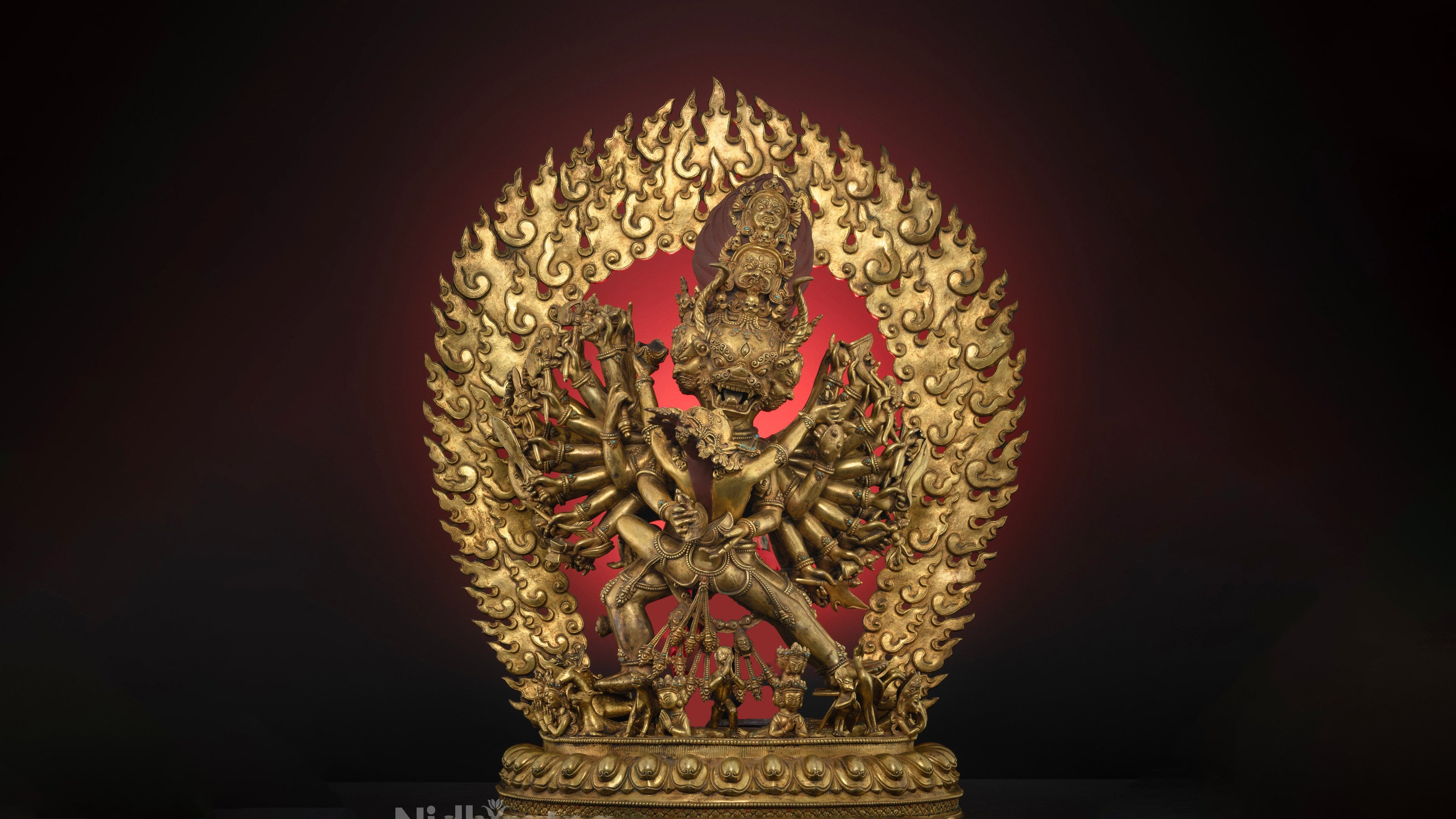 Gold plated masterpiece yamantaka statue with a fire in the background. The statue has many small intricate details