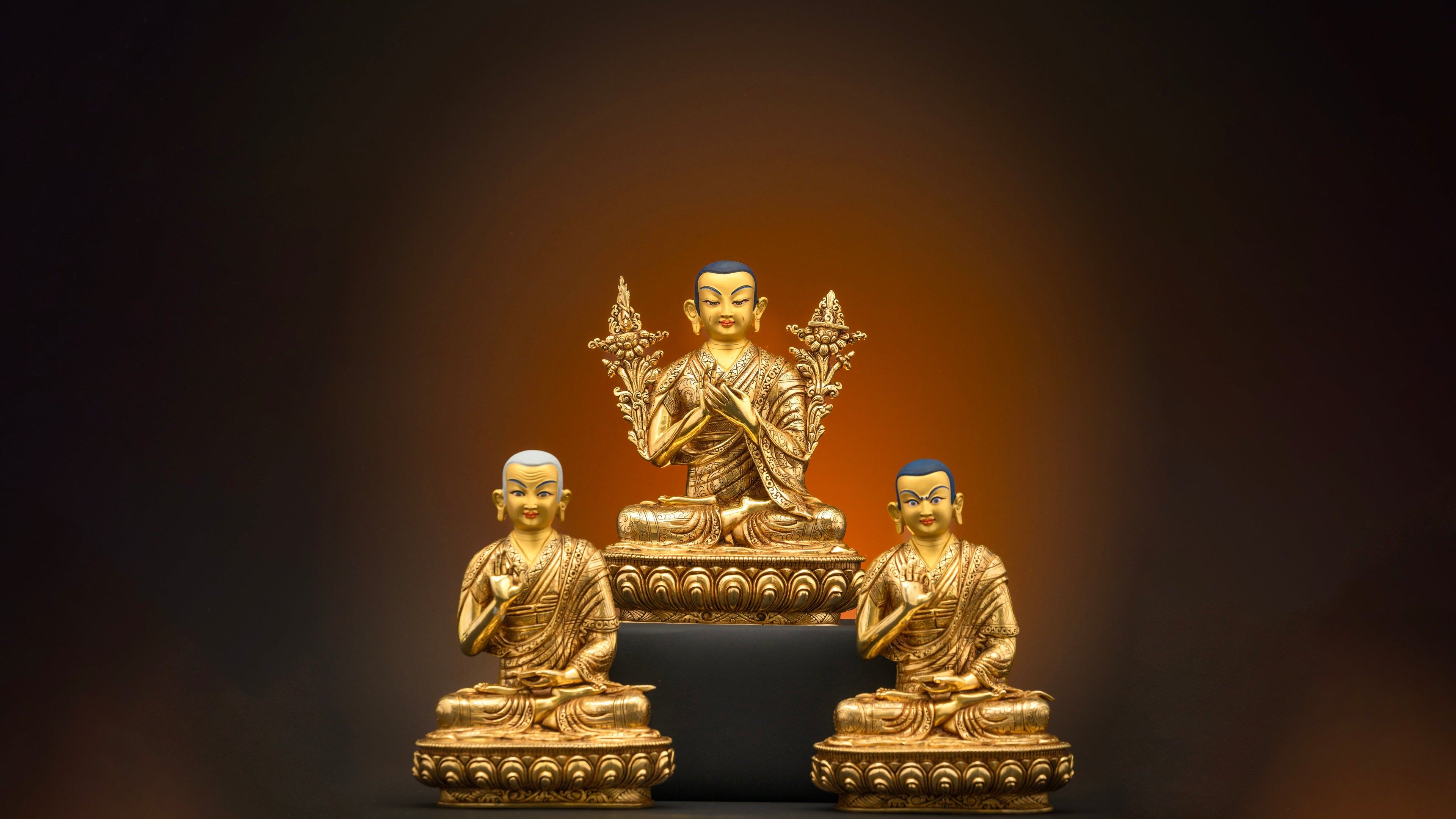 three statues of Tsongkhapa set with each statue doing a specific pose 