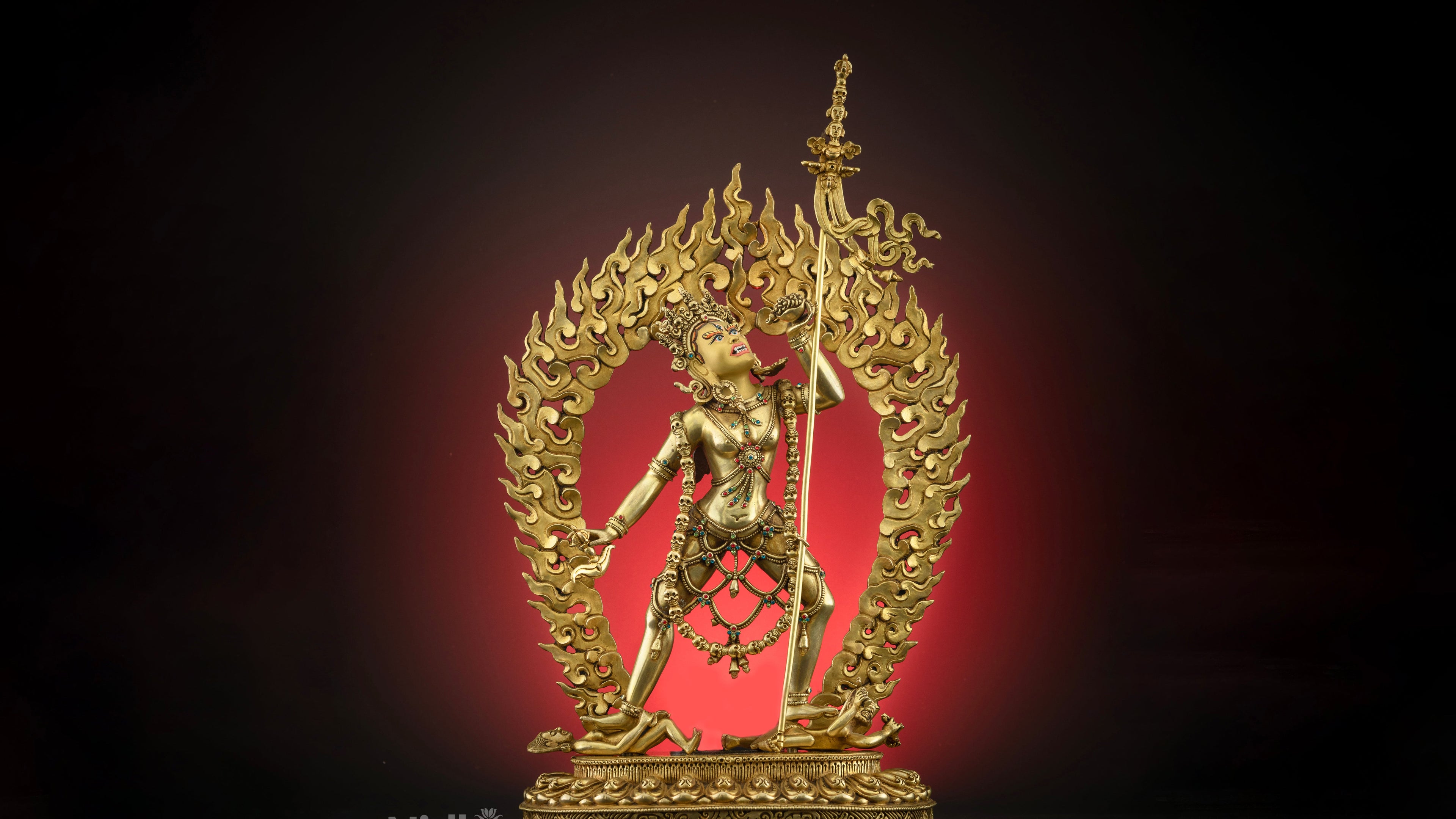 fierce gold plated vajrayogini statue with a fire in her background 