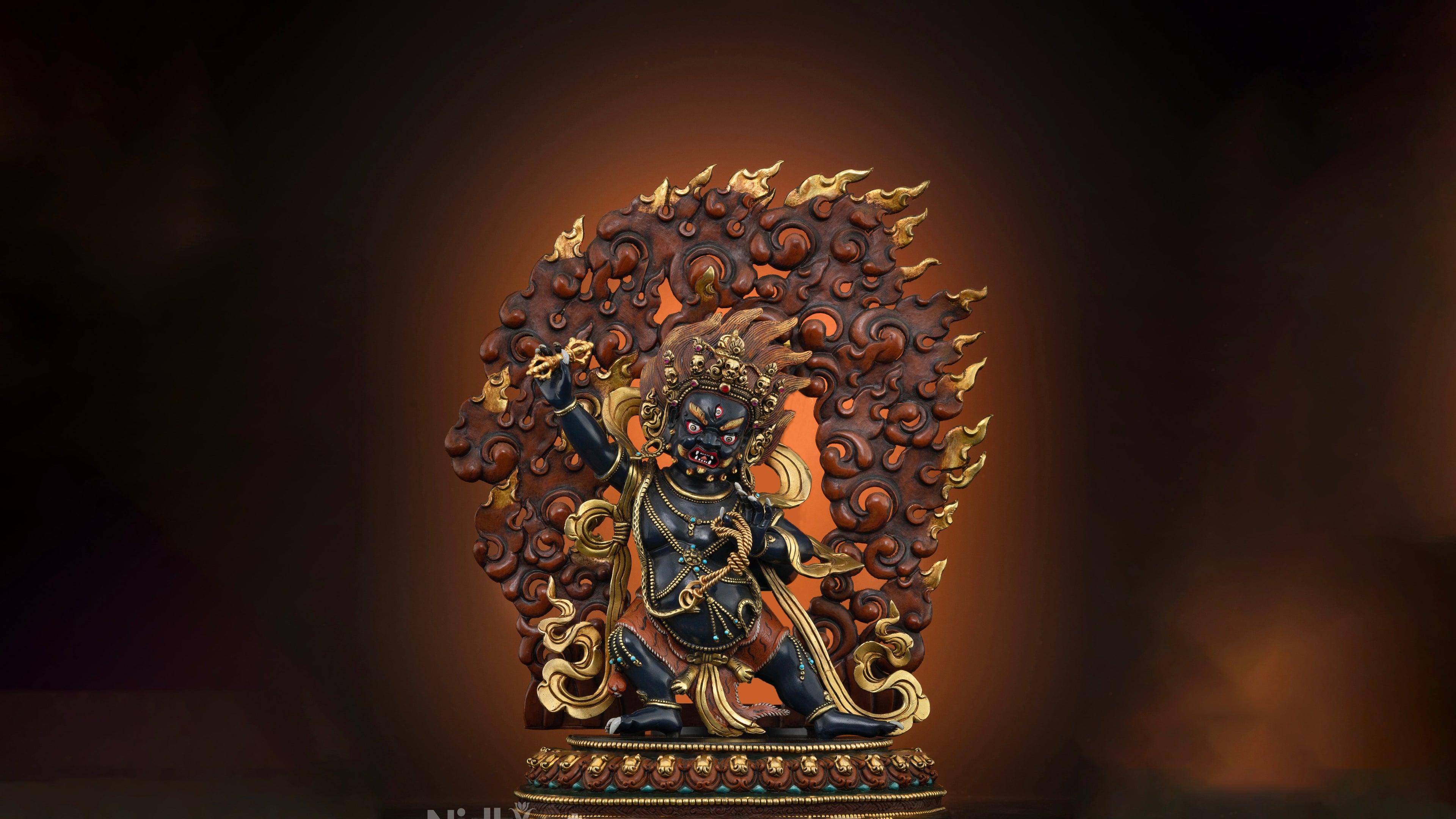 statue of fierce wrathful deity vajrapani who has black skin and has red fiery fire at the back with gold accents throughout the statue