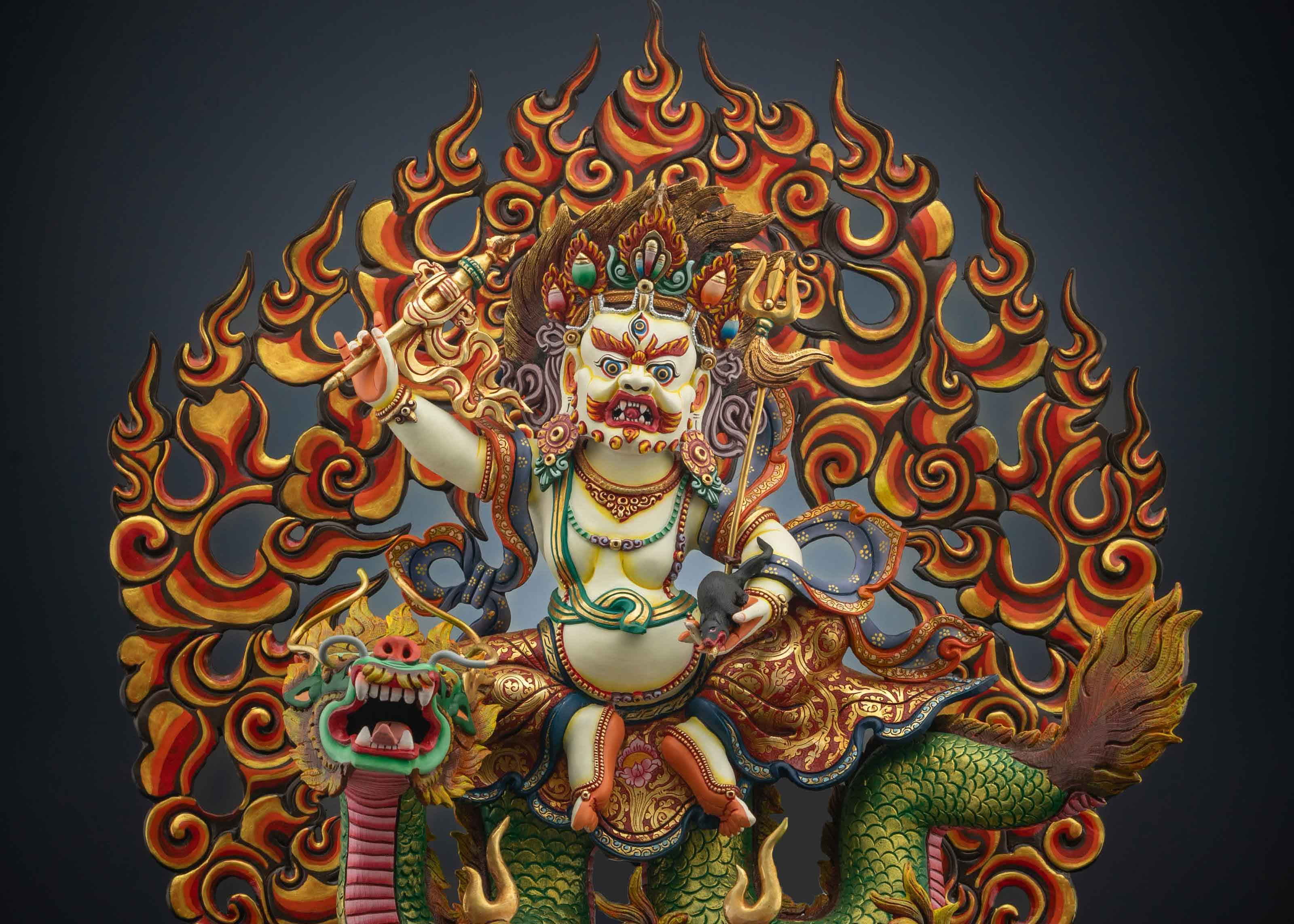 gold plated white dzambhala statue with a fire colored red and orange at his back