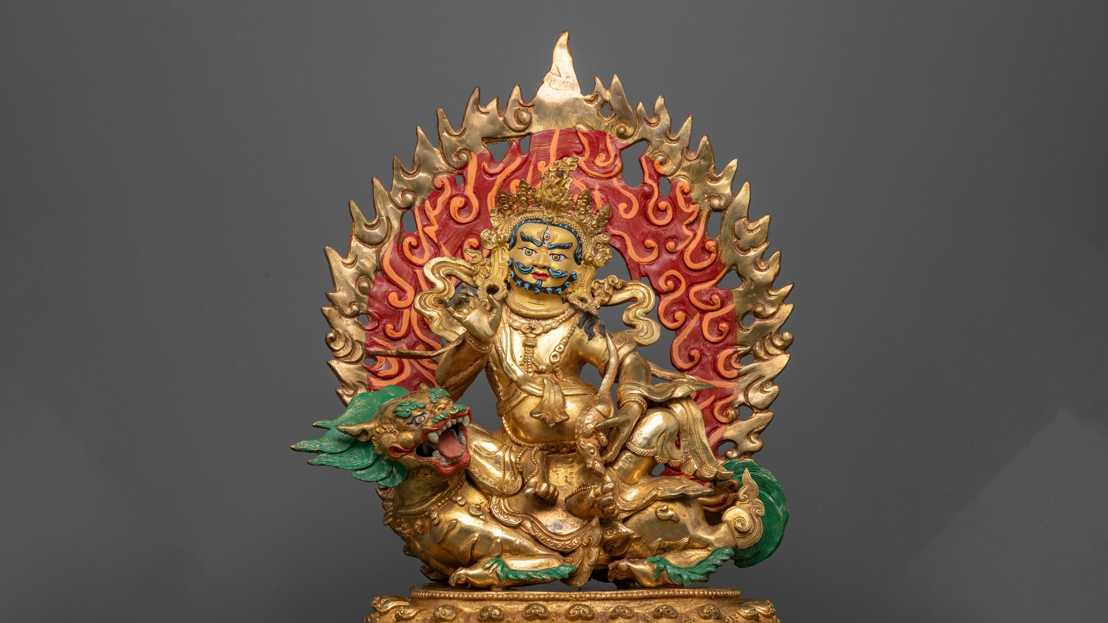 gold plated white dzambhala statue with a fire colored red and orange at his back