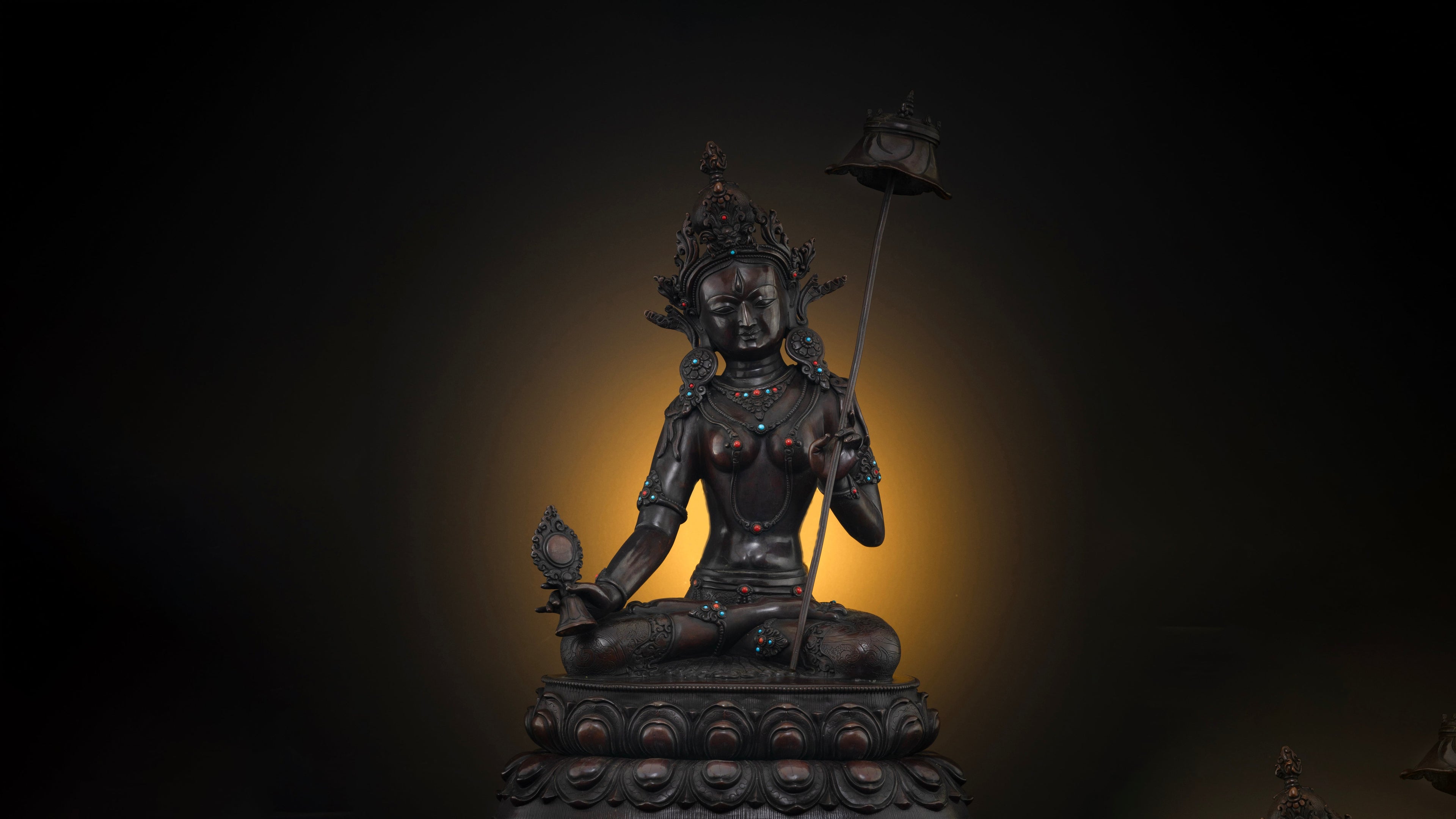 Oxidized copper dark brown statue of Dukkar with a dark background with a golden glow