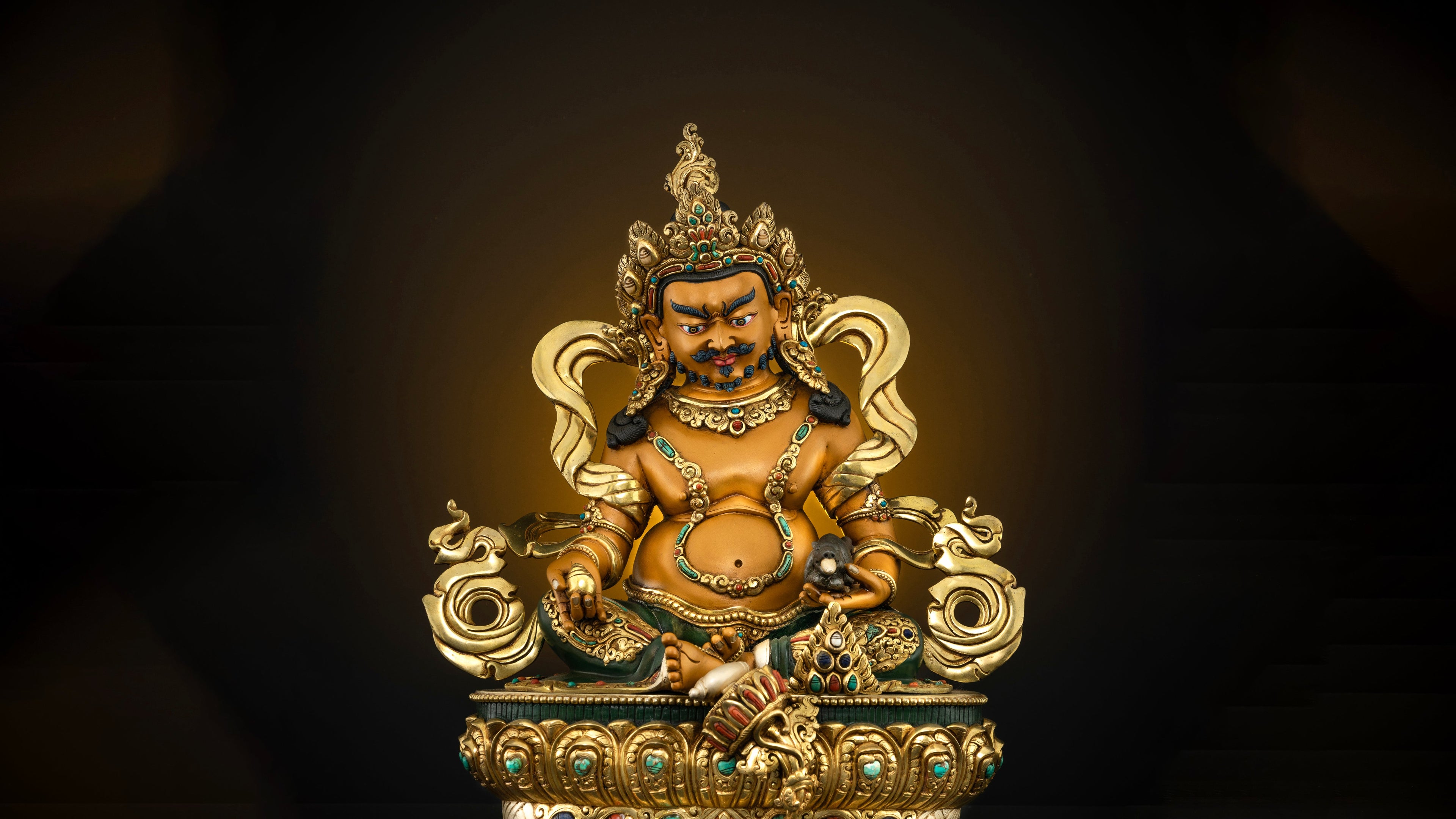 Golden statue of fat Dzambhala sitting graciously on a seat and giving out generous gifts