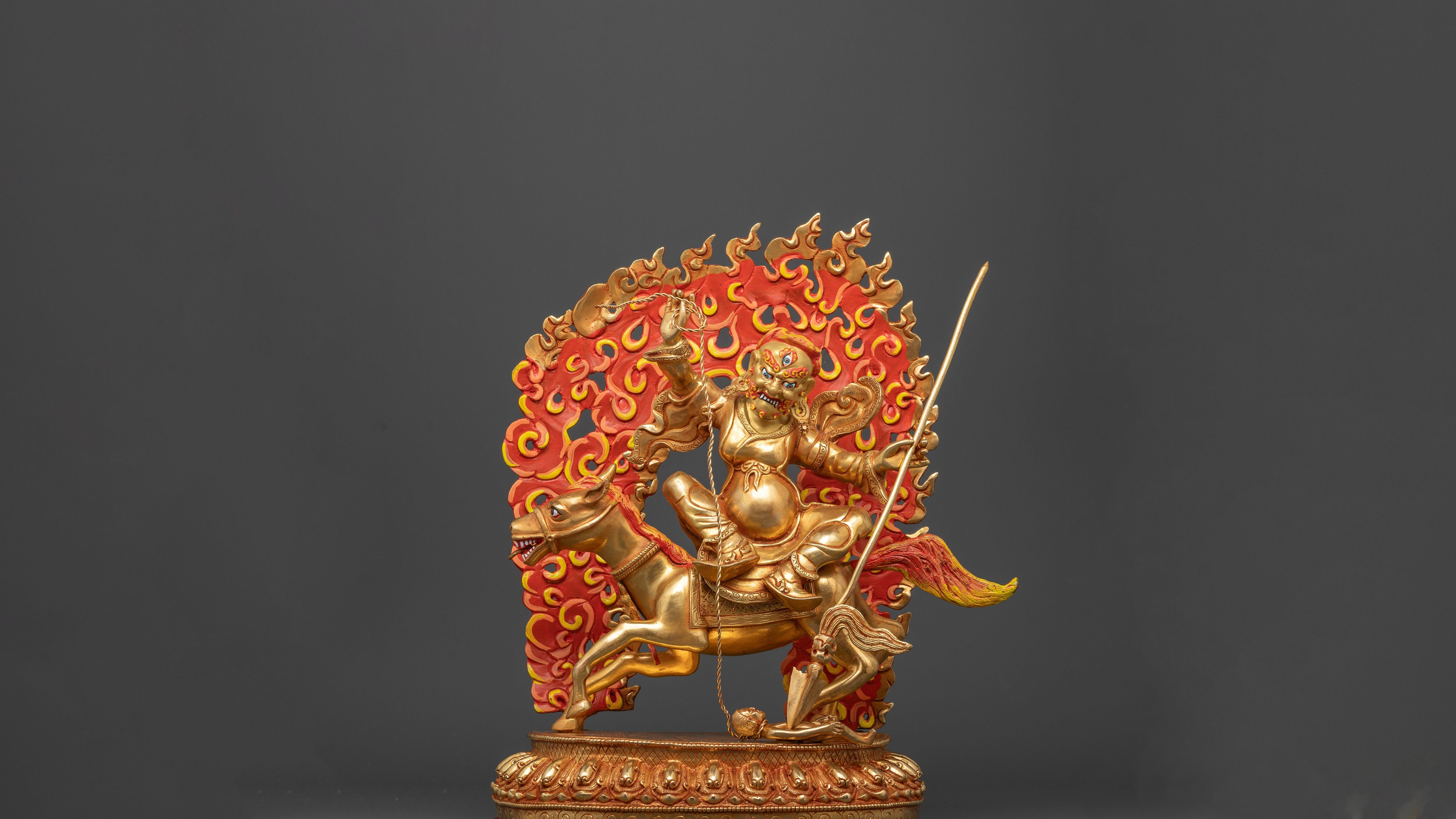 gold plated statue of Tsengo Rolpa Chudan with a fire as a background of the deity