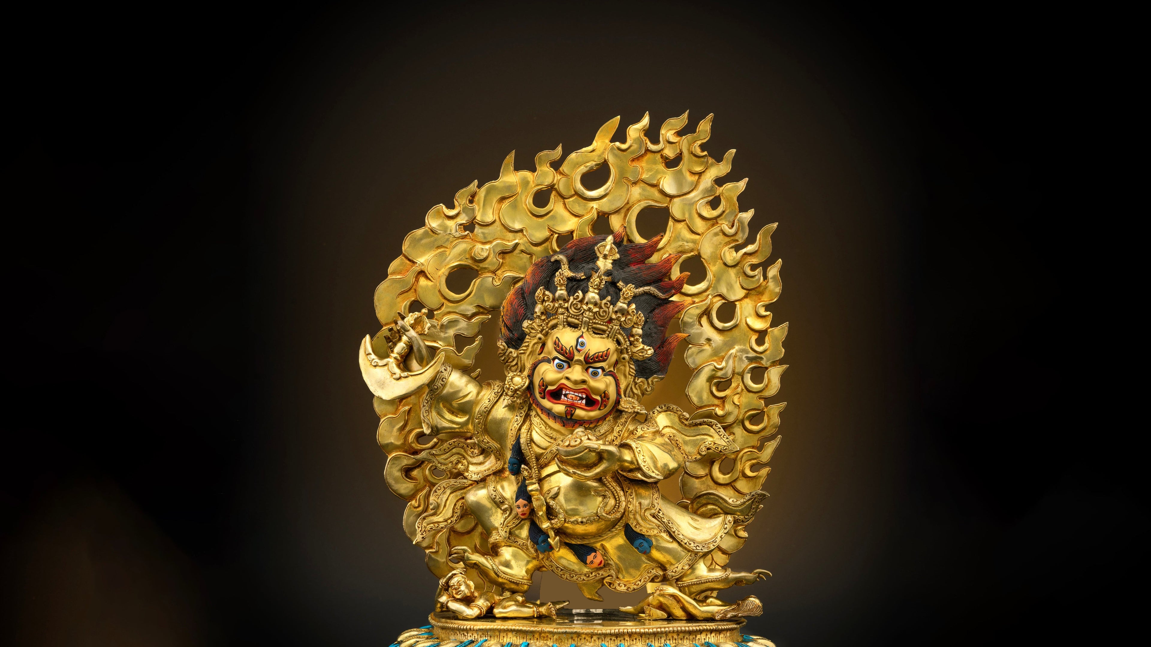 Golden statue of revered Mahakala Bernagchen with golden flames as backdrop and accented with acrylic and poster colors