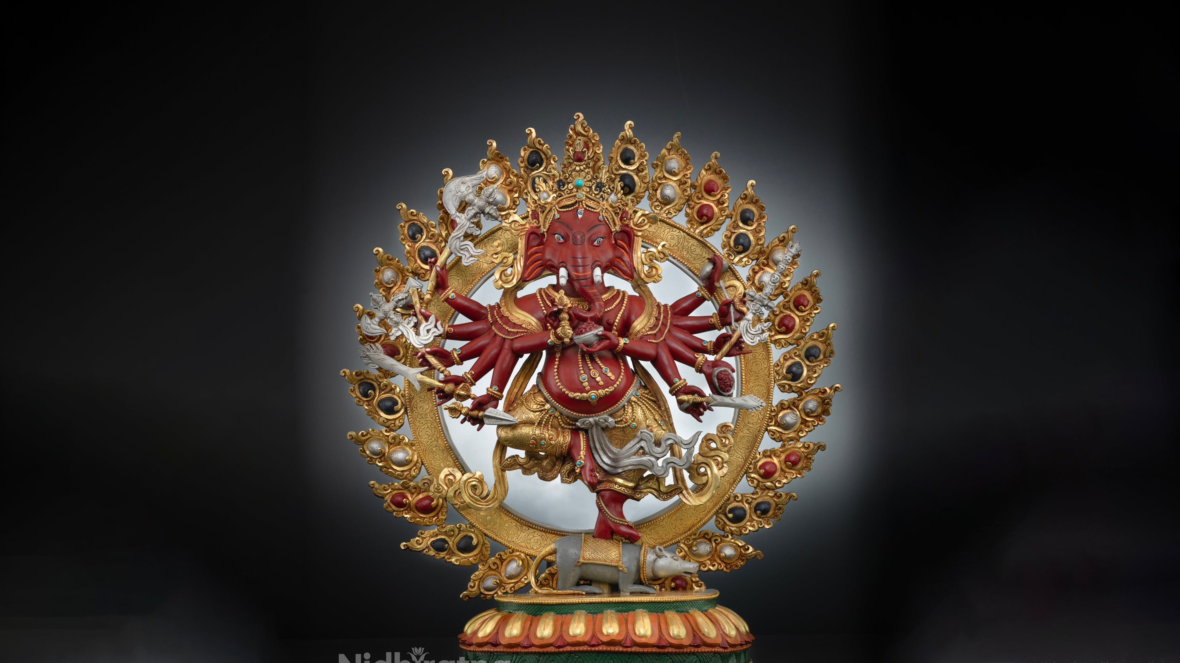 Golden statue of Elephant head god ganesh with red color accents and other gemstones embedded on the statue